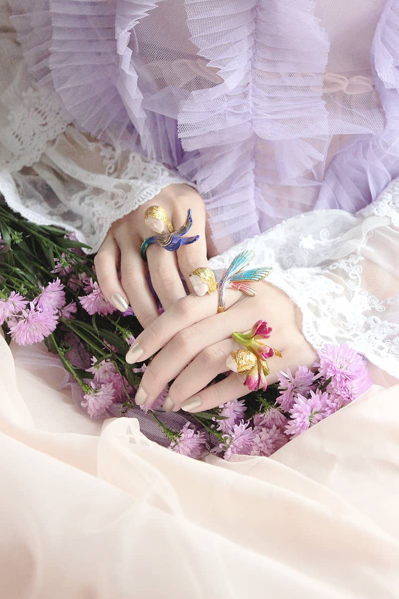 Fantasy-inspired, a mermaid, a nymph, and a fairy ring showcased on hands surrounded by flowers.