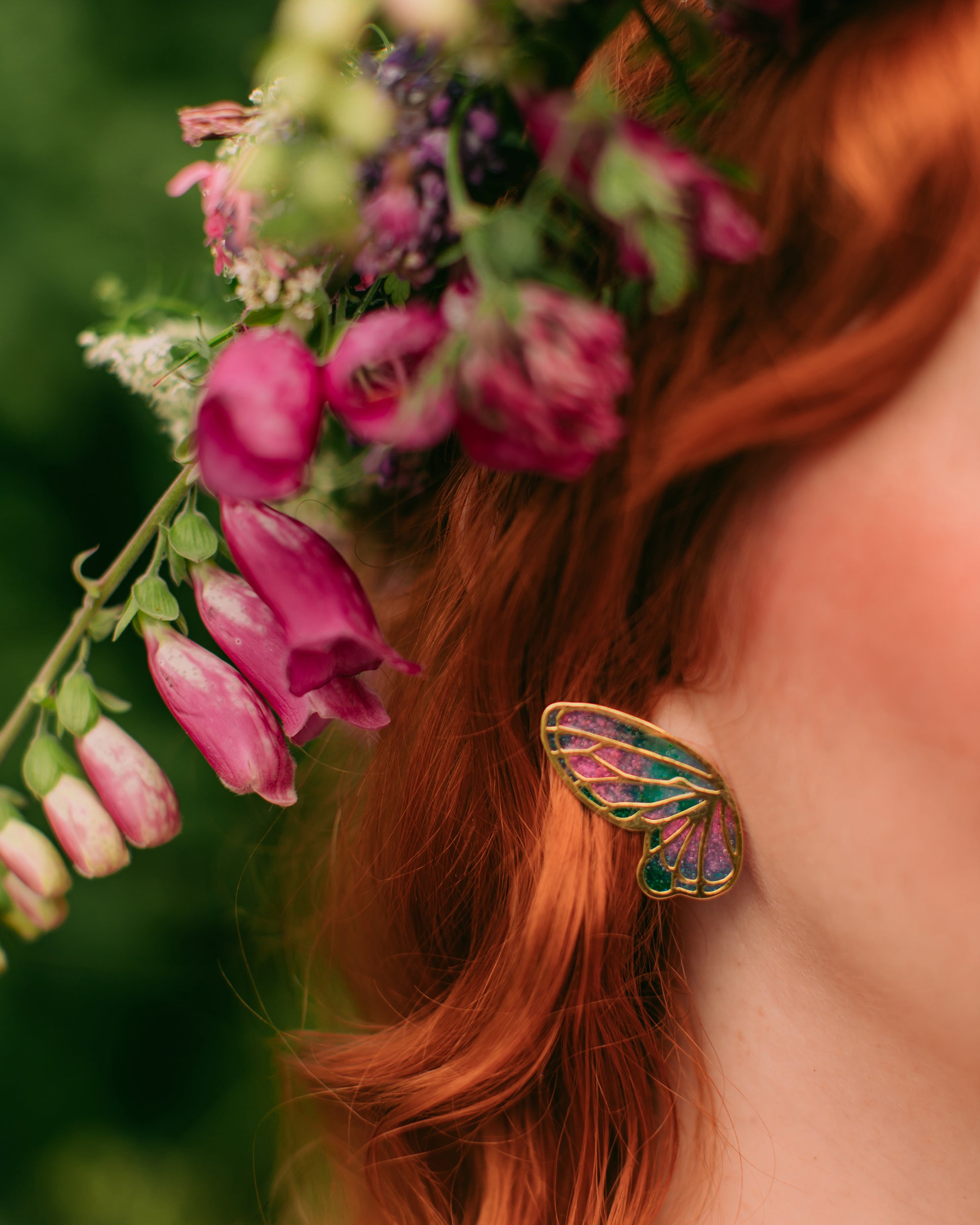 Close-up of a model with colorful butterfly earrings and a vibrant flower crown.