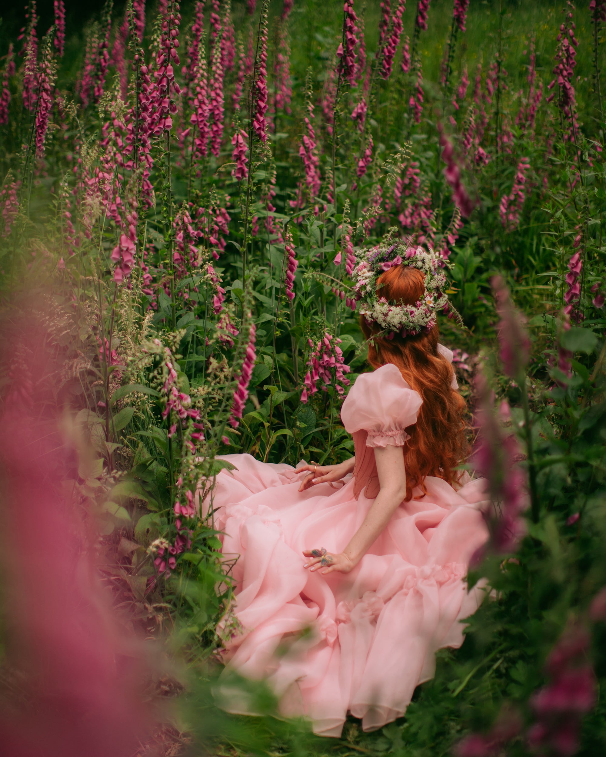 A beautiful butterfly ring worn by a girl in a pink dress surrounded by flowers.