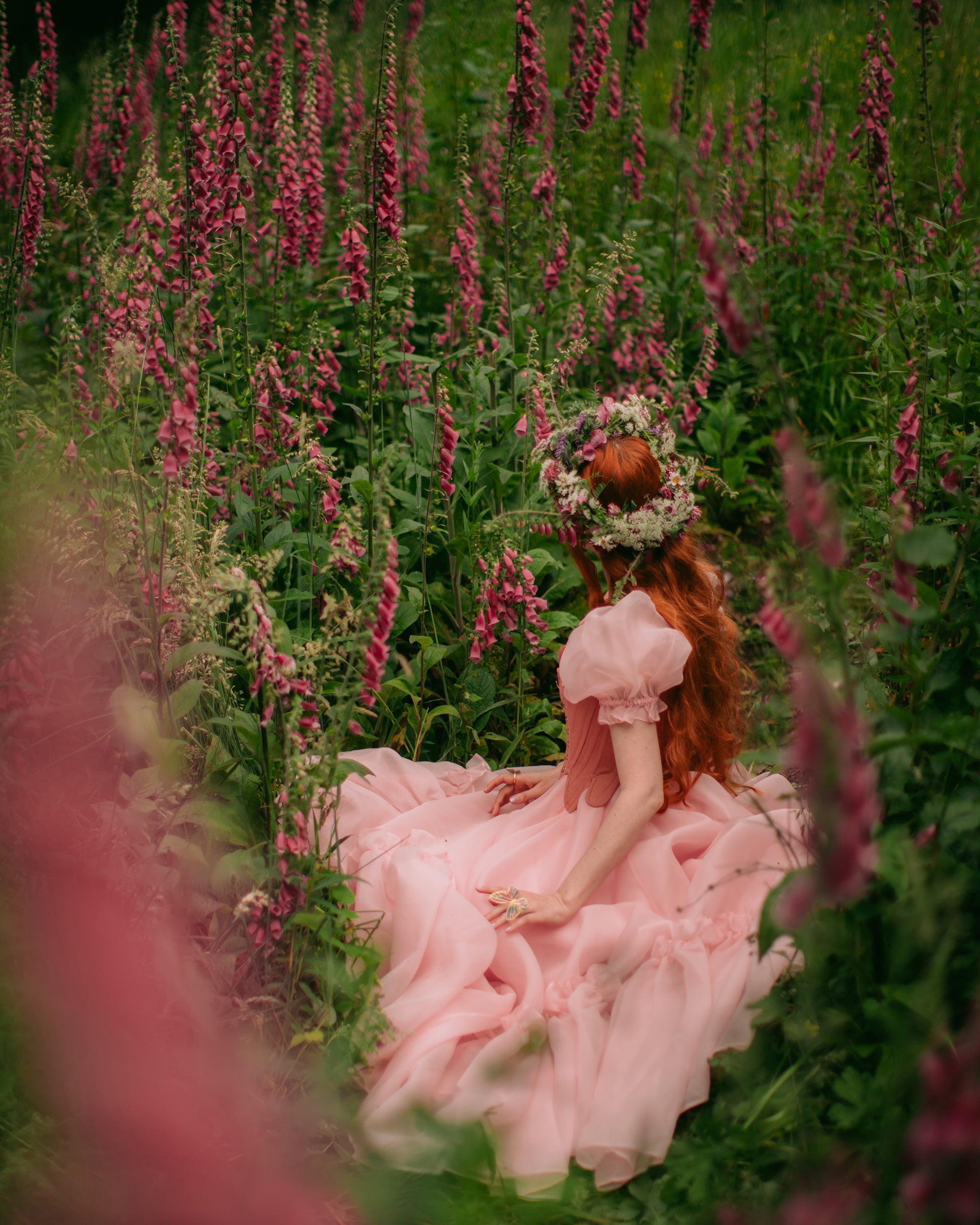 A beautiful butterfly ring worn by a girl in a pink dress surrounded by flowers.