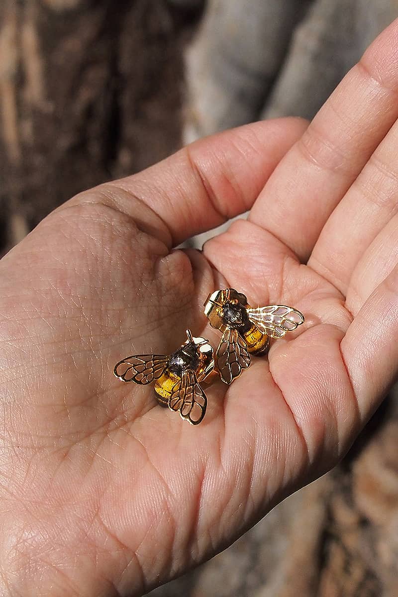 Close-up of charming bee earrings held in hand