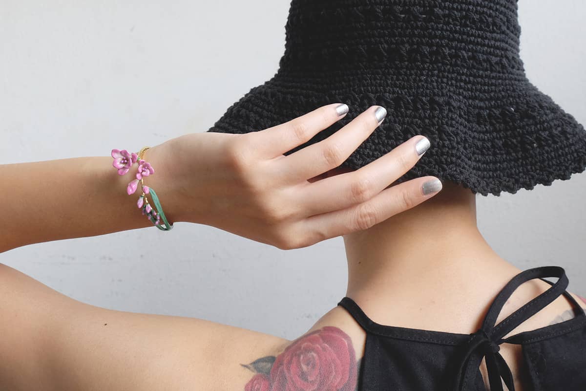 Summer fashion featuring a black hat and a colorful floral bangle.