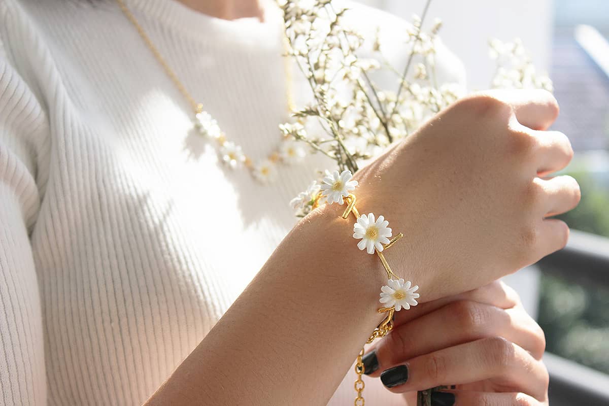 Close-up of a hand adorned with a floral bracelet holding dried flowers.