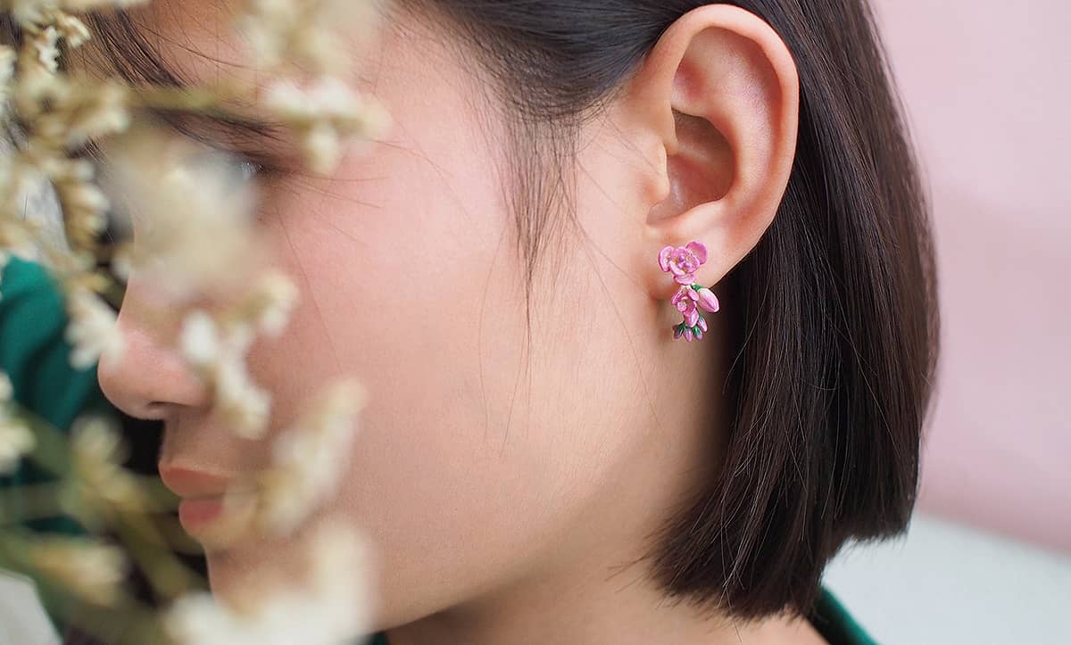 Close-up of pink flower earrings worn on a woman's ear