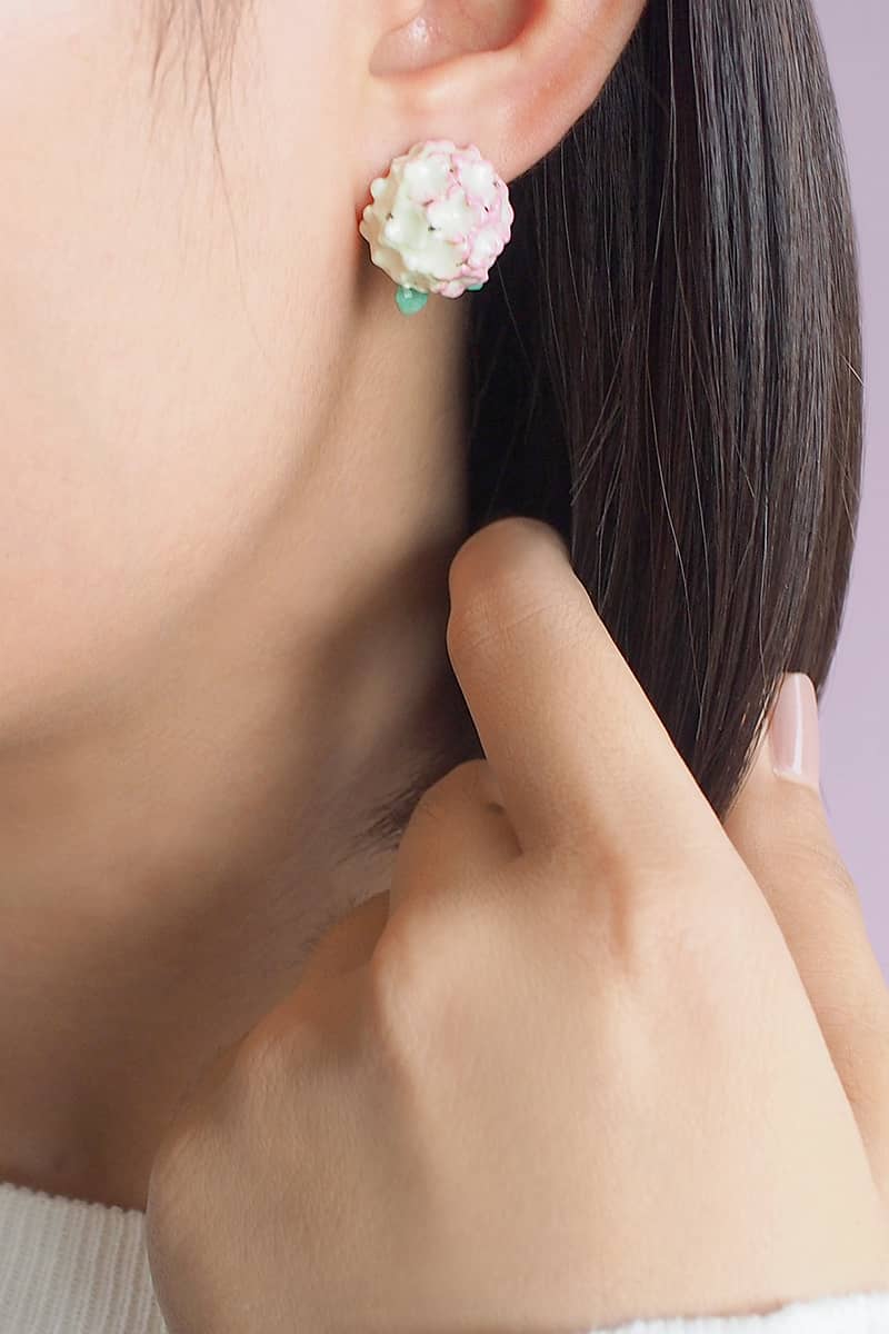 Close-up of hydrangea-themed earrings worn by a model.