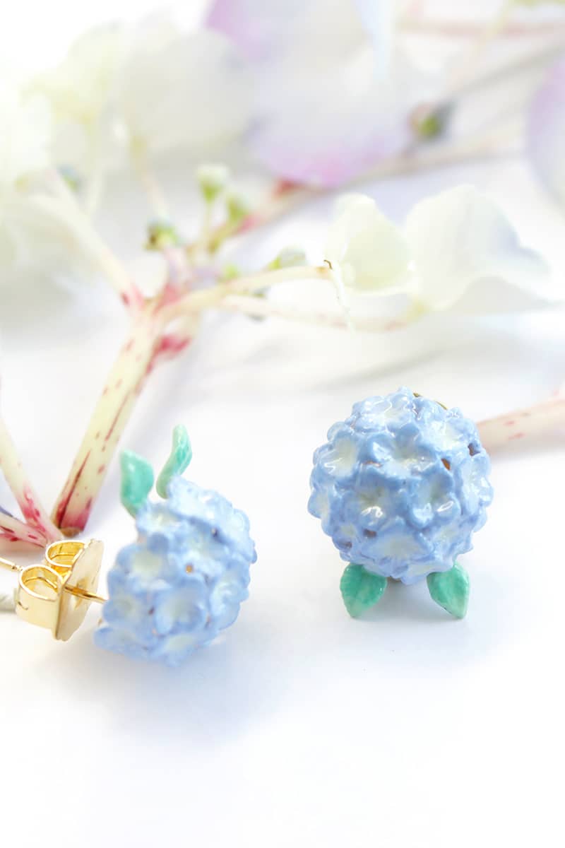 Artisan-crafted flower earrings with a delicate green leaf design among flower setting.