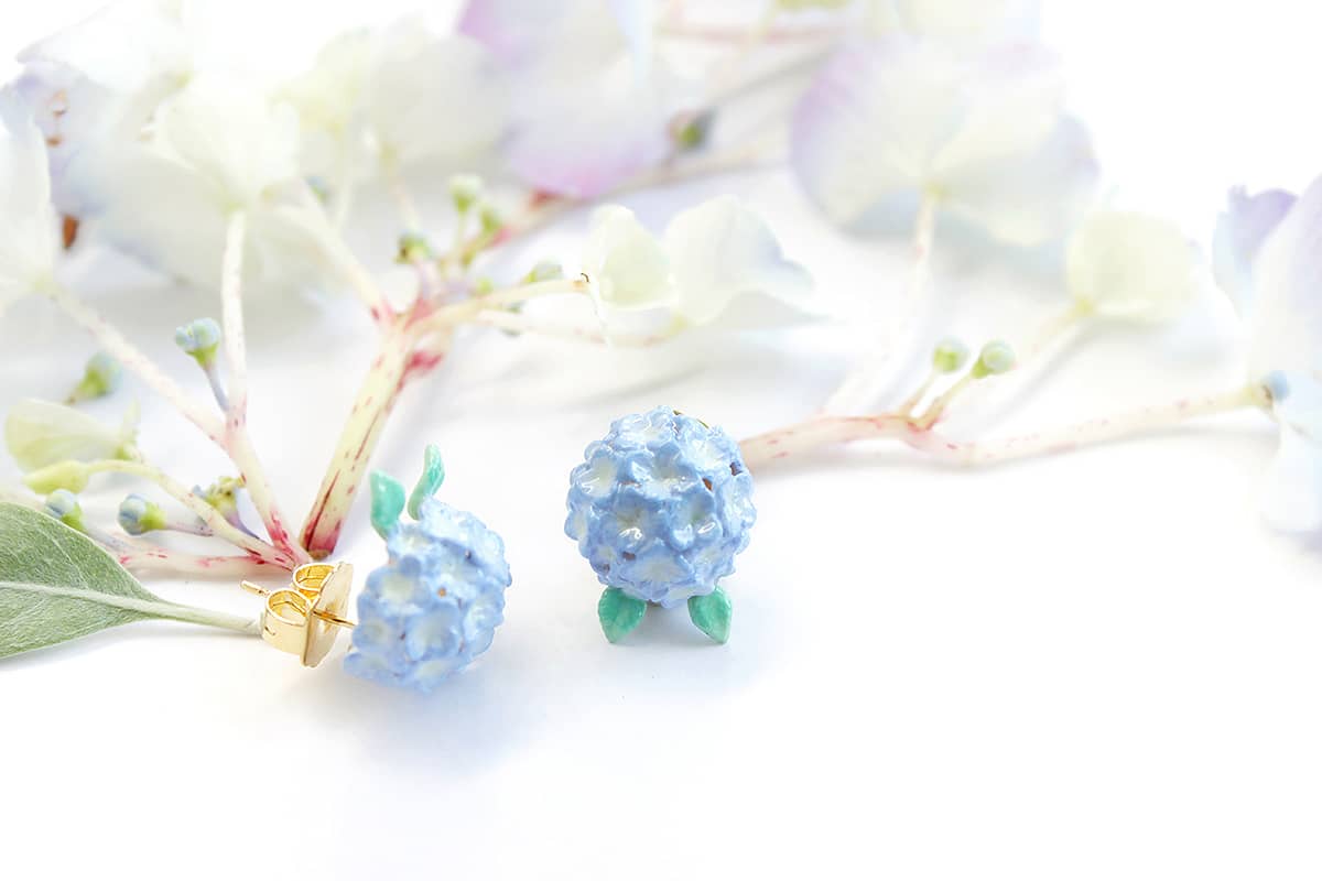 Artisan-crafted flower earrings with a delicate green leaf design set in flower setting.