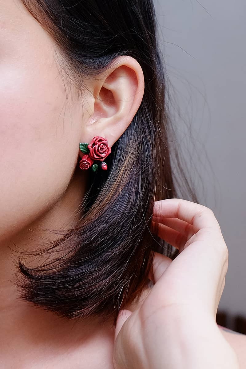 Close-up of stunning red rose earring worn on a woman with short black hair.