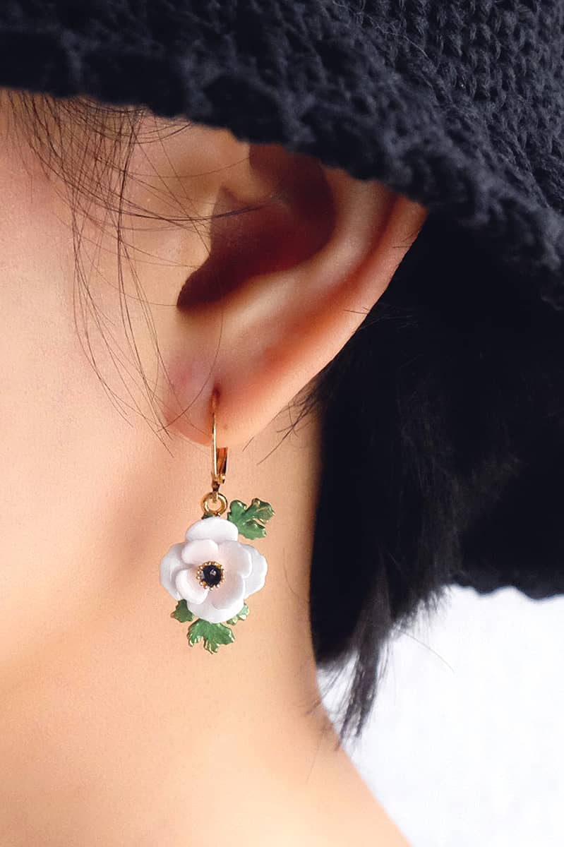 Close-up of a model wearing a unique white flower earring design.