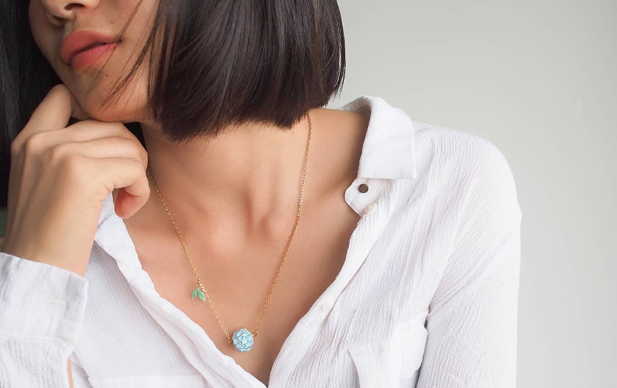 Charming floral pendant featuring a hydrangea design worn on a woman's neck.