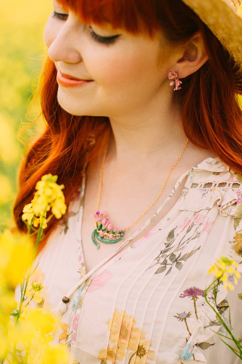 Close-up of a woman with red hair wearing floral earrings and necklace