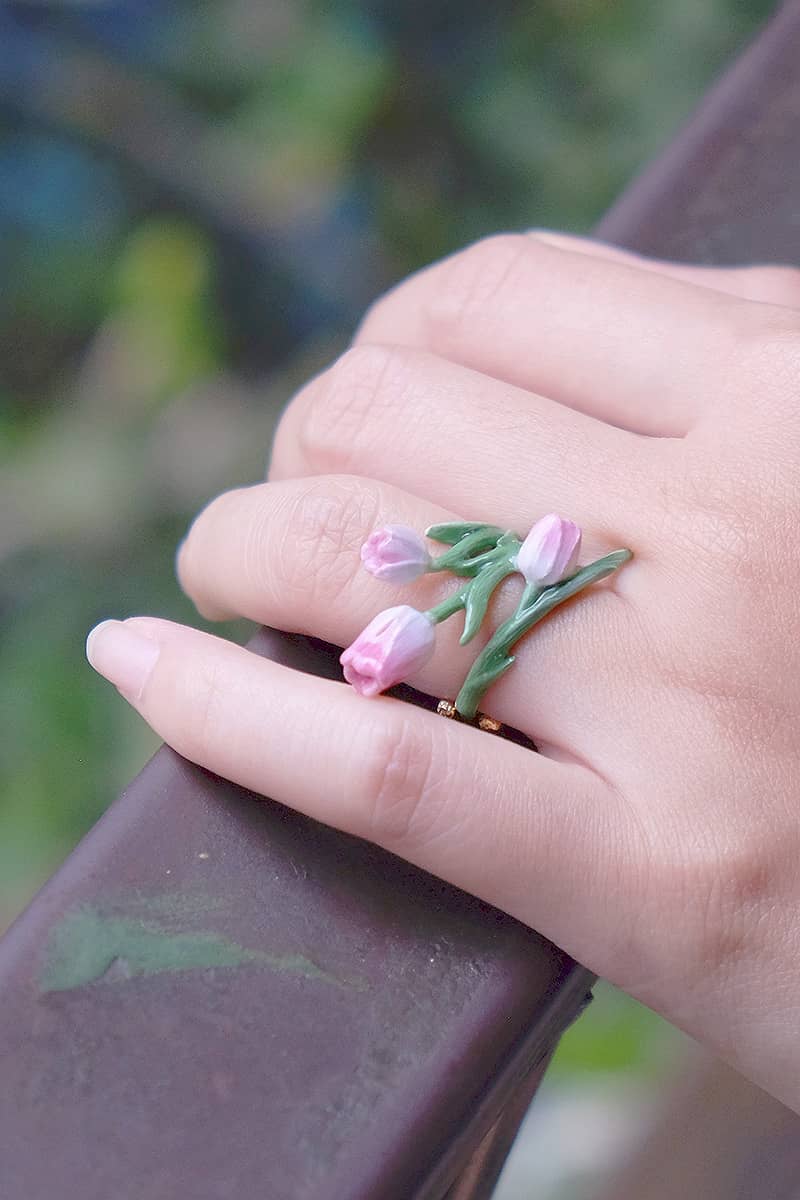 Close-up of a hand wearing a beautiful tulip ring while holding a wooden rail.