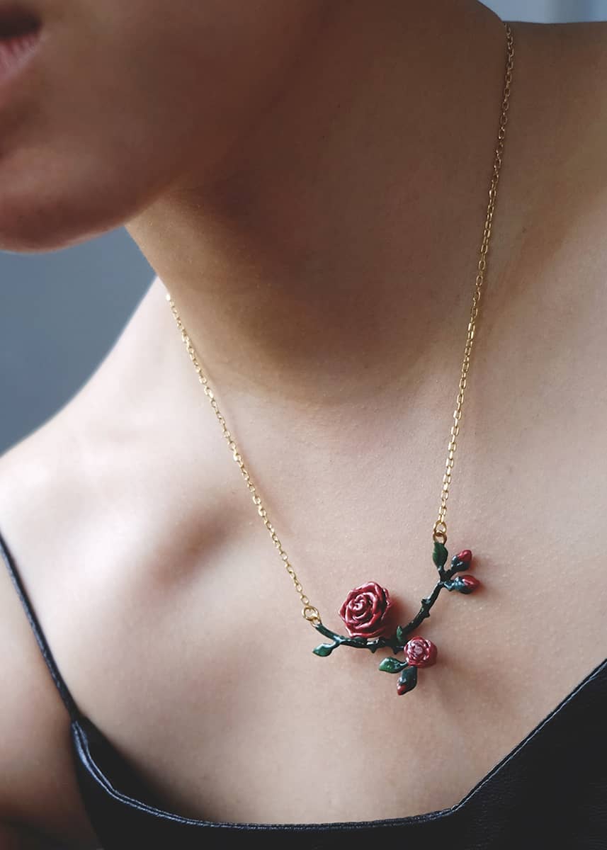 Close-up of a person wearing a red rose necklace, ideal for summer fashion.