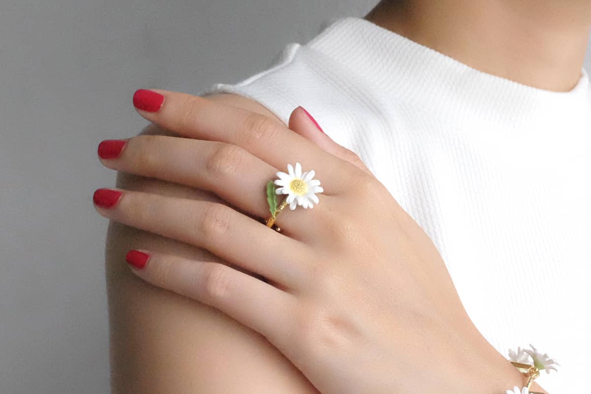 Close-up of a hand wearing a daisy ring, perfect for flower lovers.