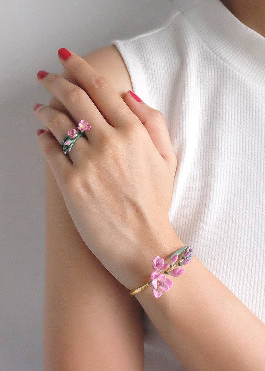 Close-up of a hand wearing a pink flower ring and matching bangle.