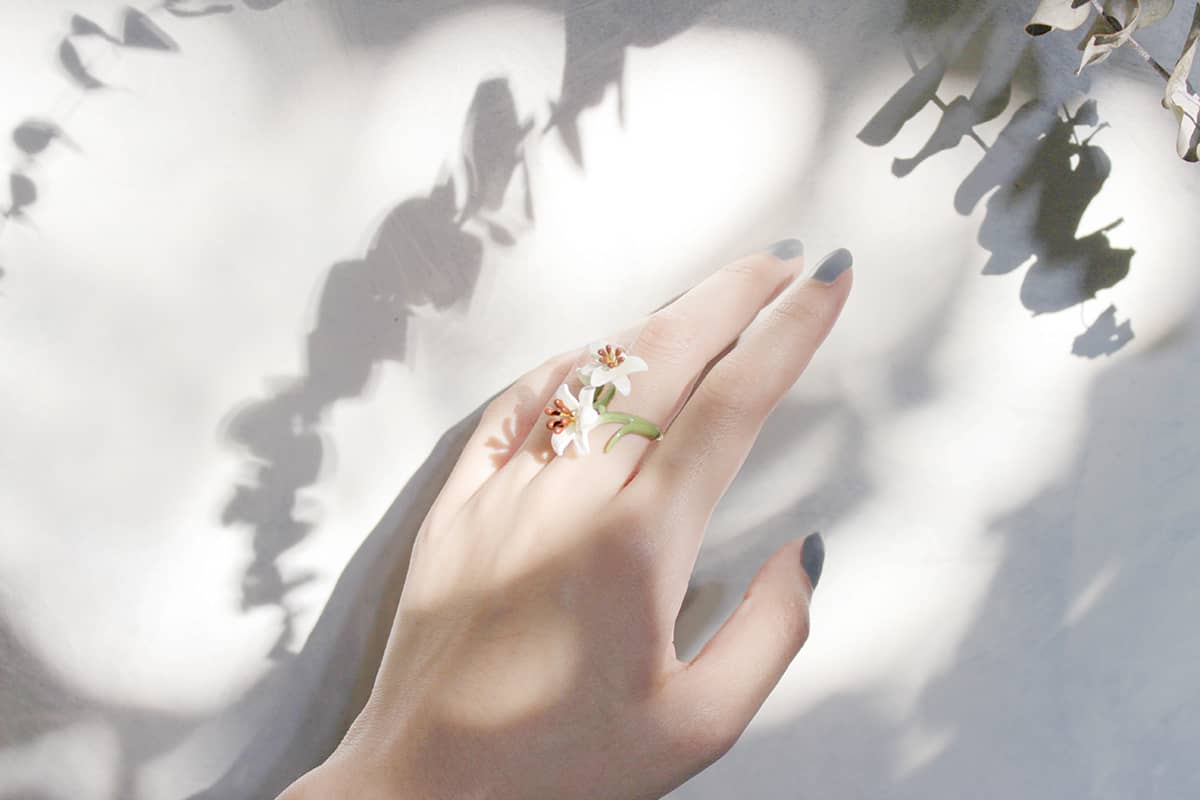 A hand adorned with a delicate floral ring featuring lily flowers design, perfect for flower lovers.