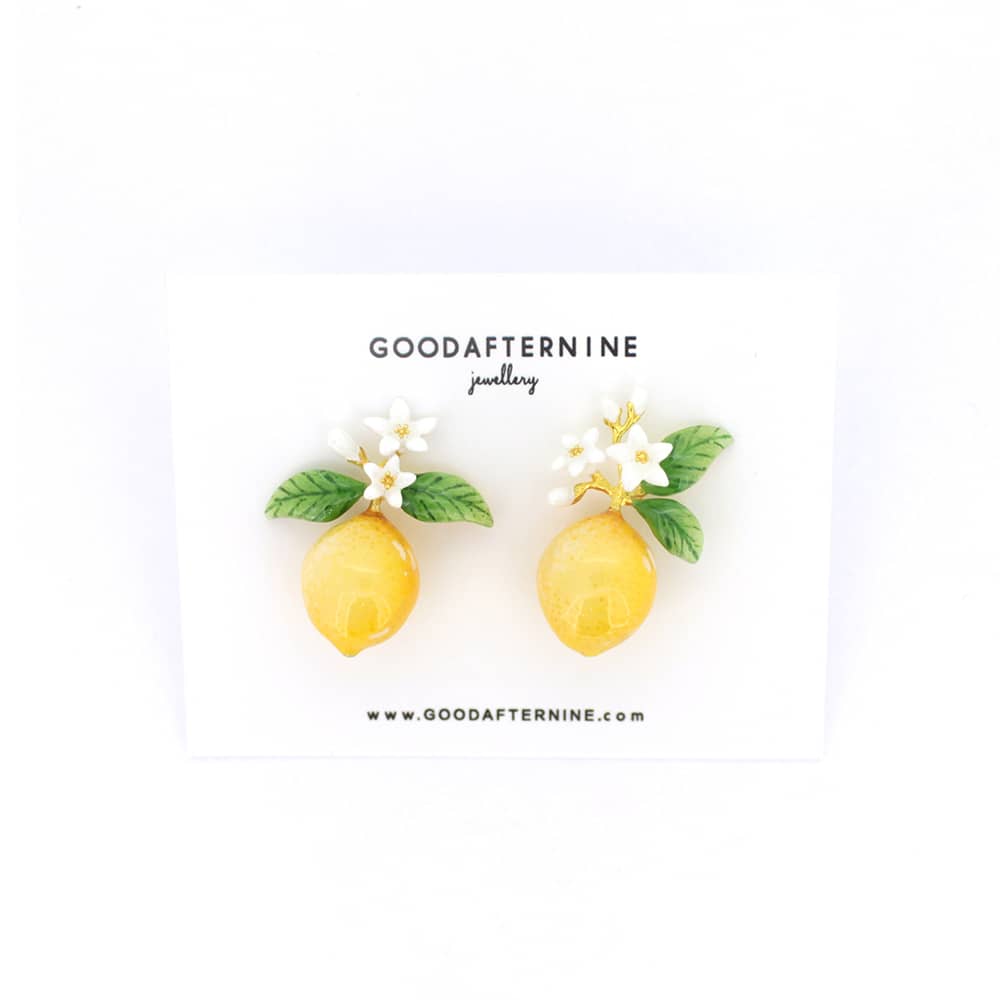 Charming yellow lemon earrings adorned with delicate white flowers and green leaves, ideal for summer fashion.