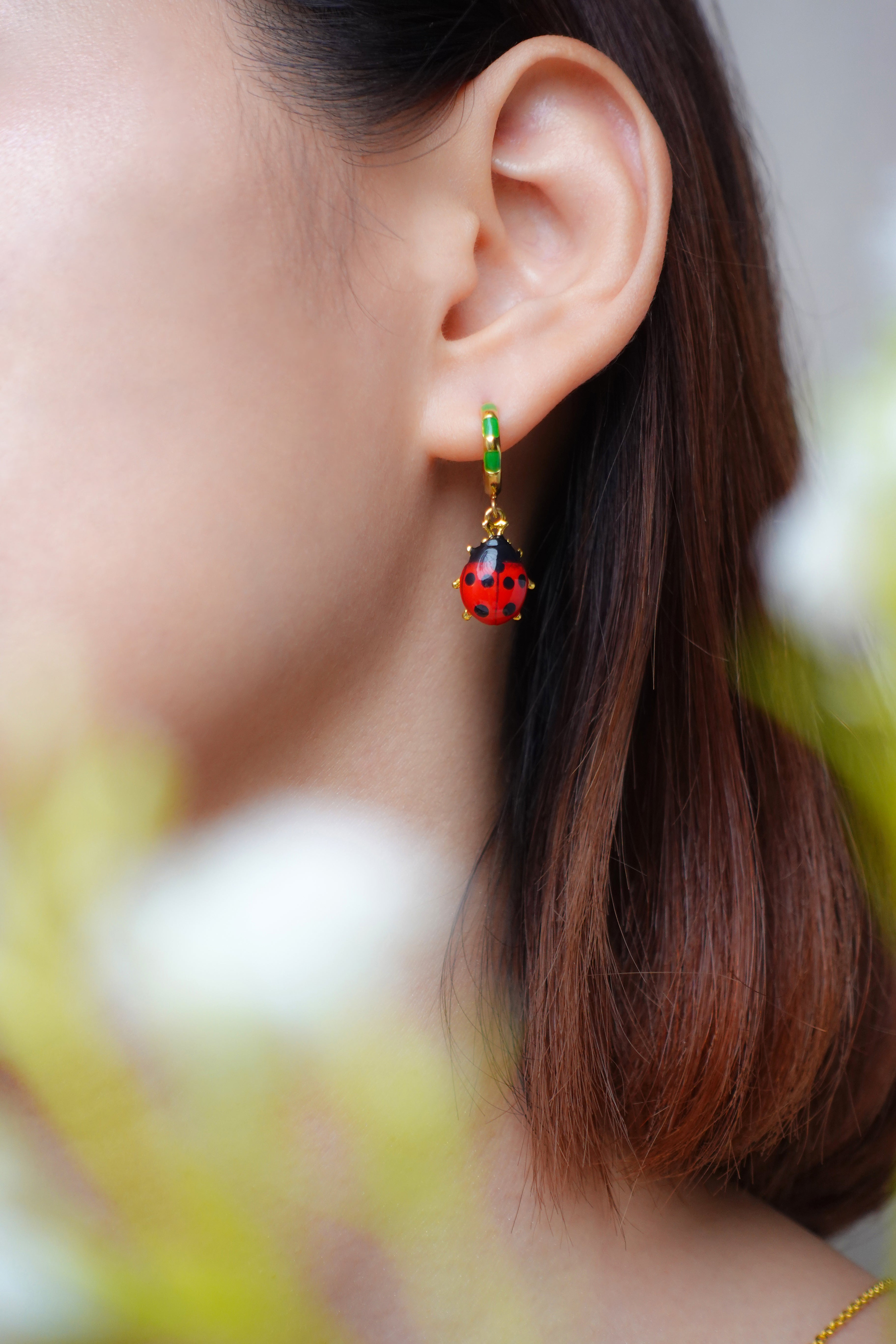 Close up of beautiful ladybug earrings on a woman's ear.