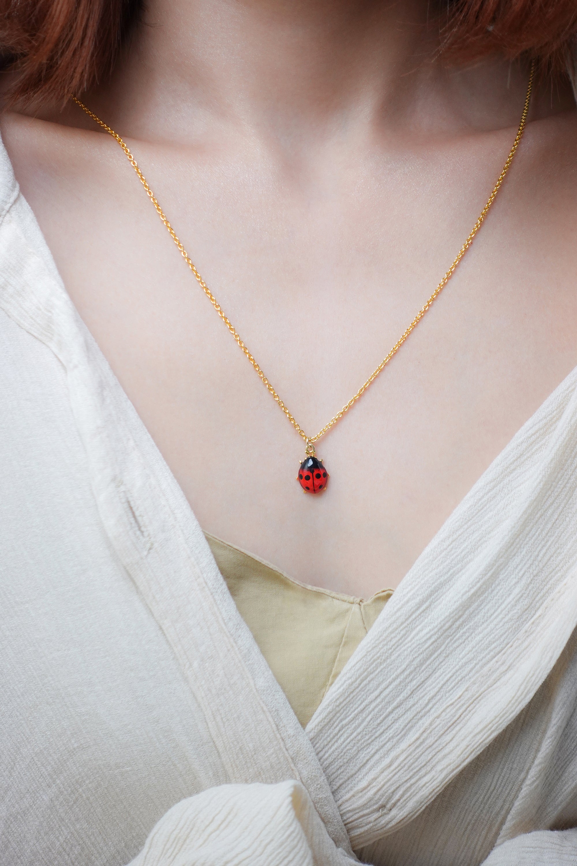 Close up of a red ladybug charm necklace with casual outfit.