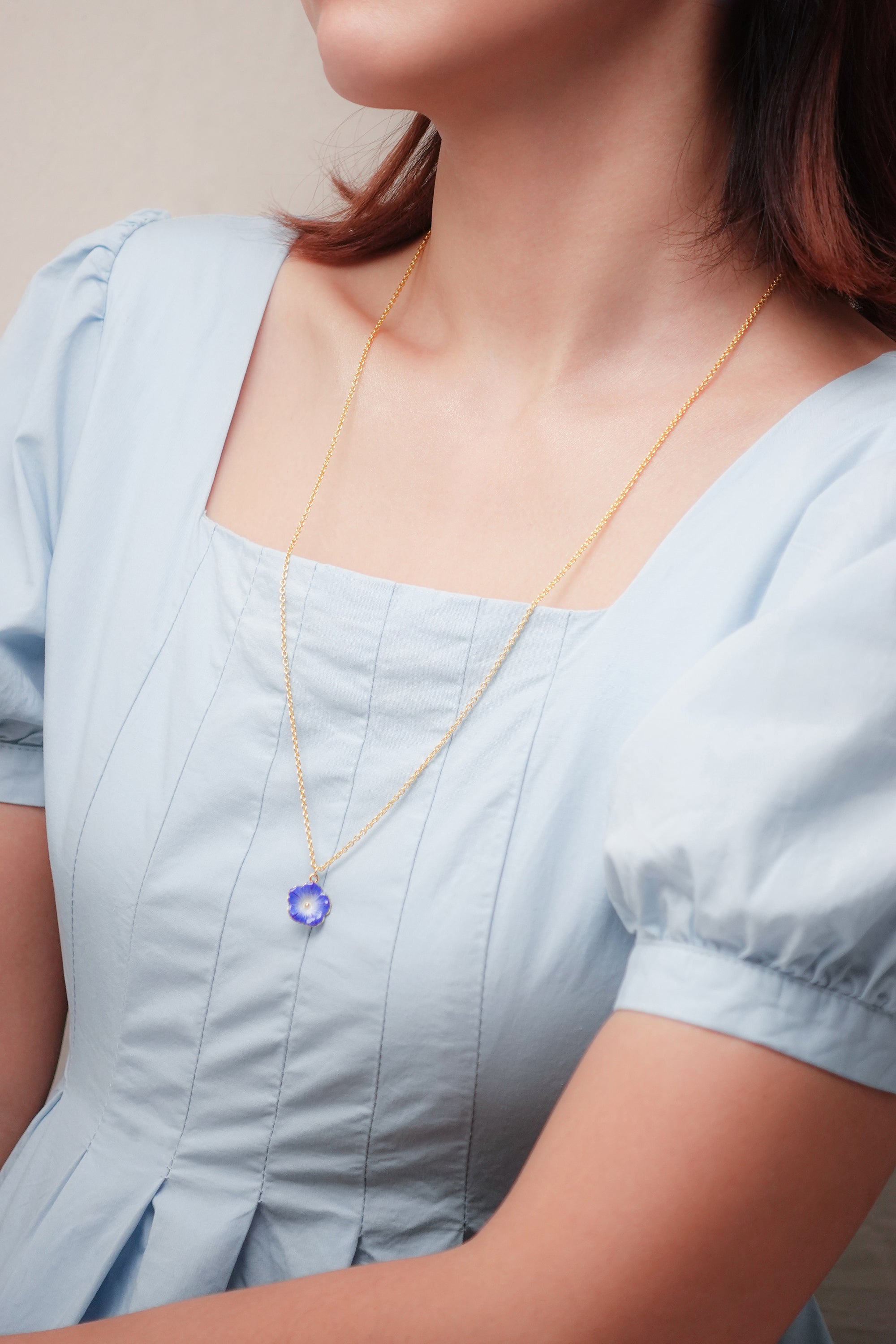 Women wearing blue floral necklace with blue dress, ideal for summer outfit.