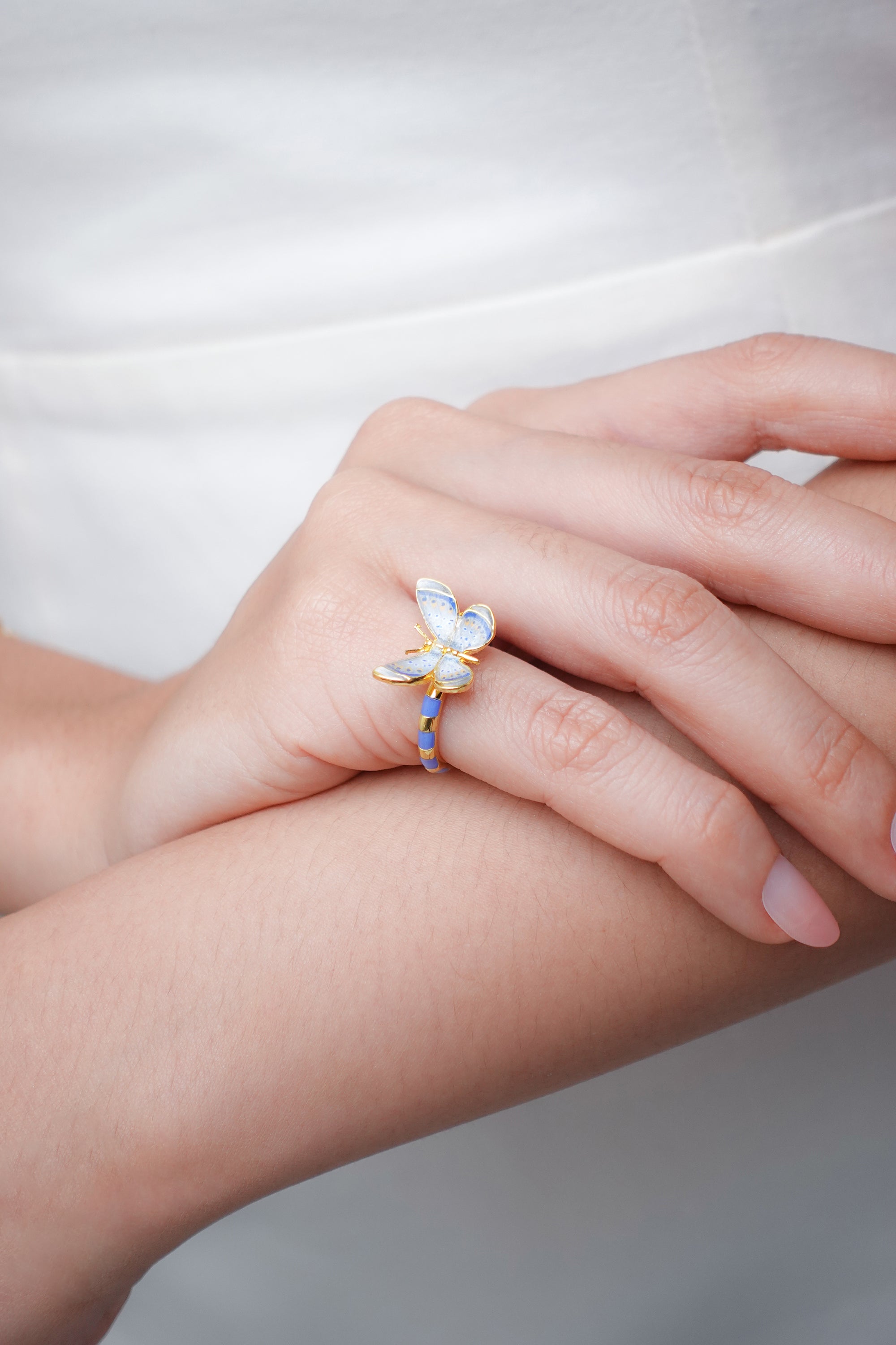 Artistic blue butterfly ring worn on a woman's hand.