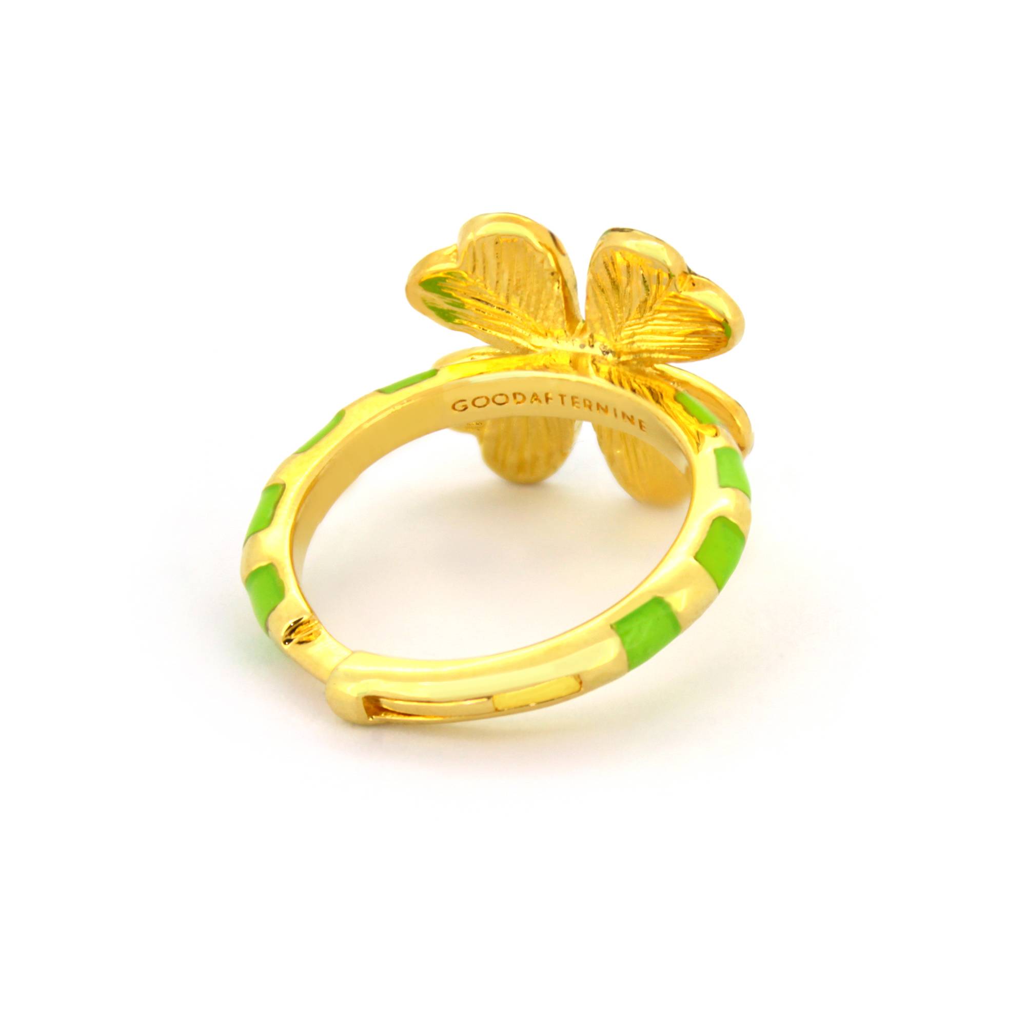 A gold ring featuring a green four-leaf clover design, with a striped band in green and gold accents.