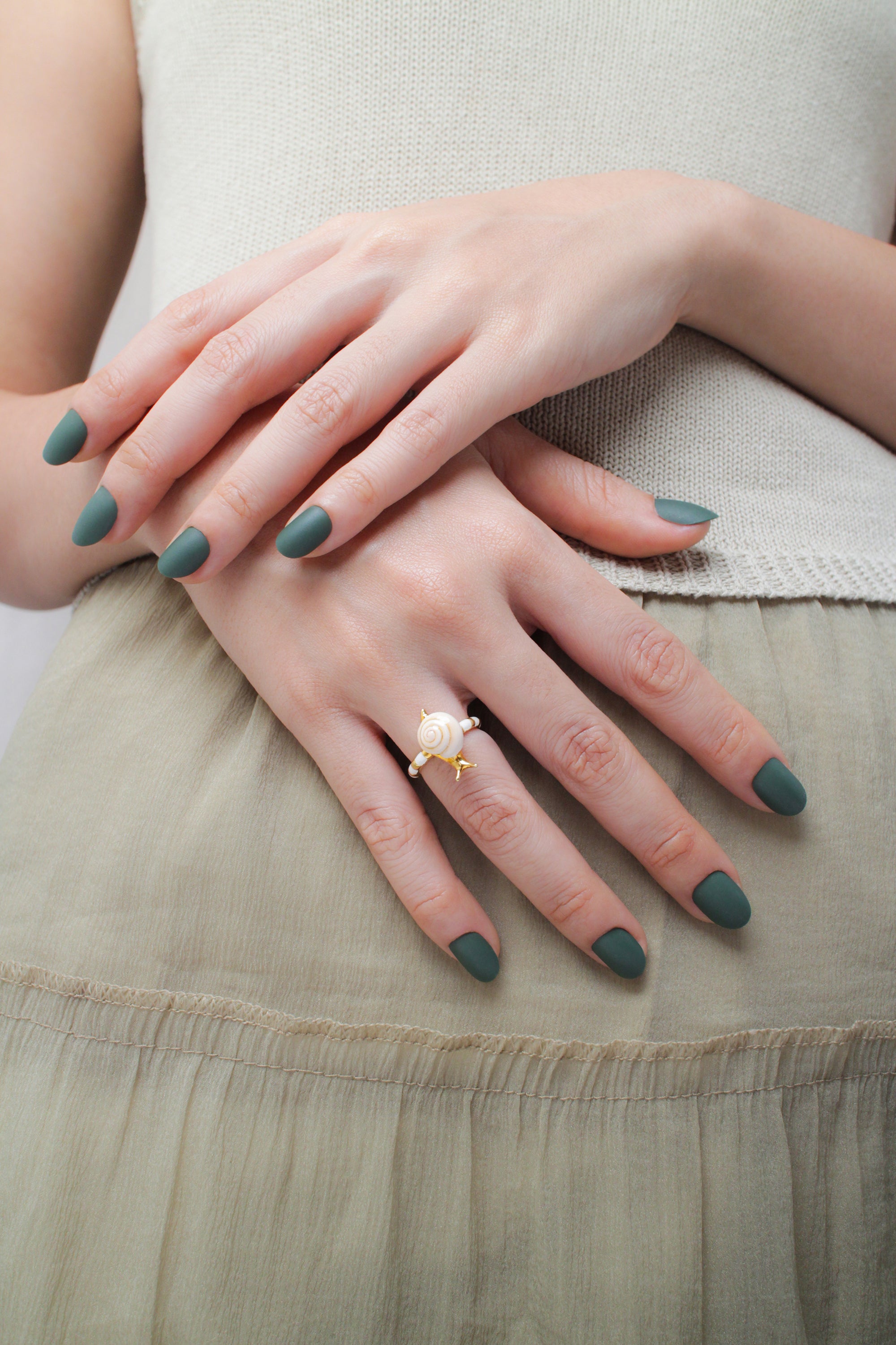 Close-up of a hand with green nail polish adorned with a charming snail ring in a casual outfit, ideal for summer fashion.