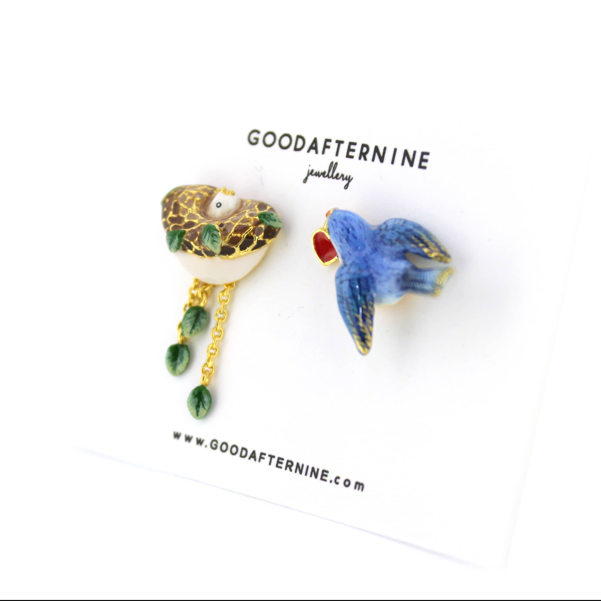 Colorful earrings featuring a bird, leaf and a nest designs, with gold accents and dangling elements.