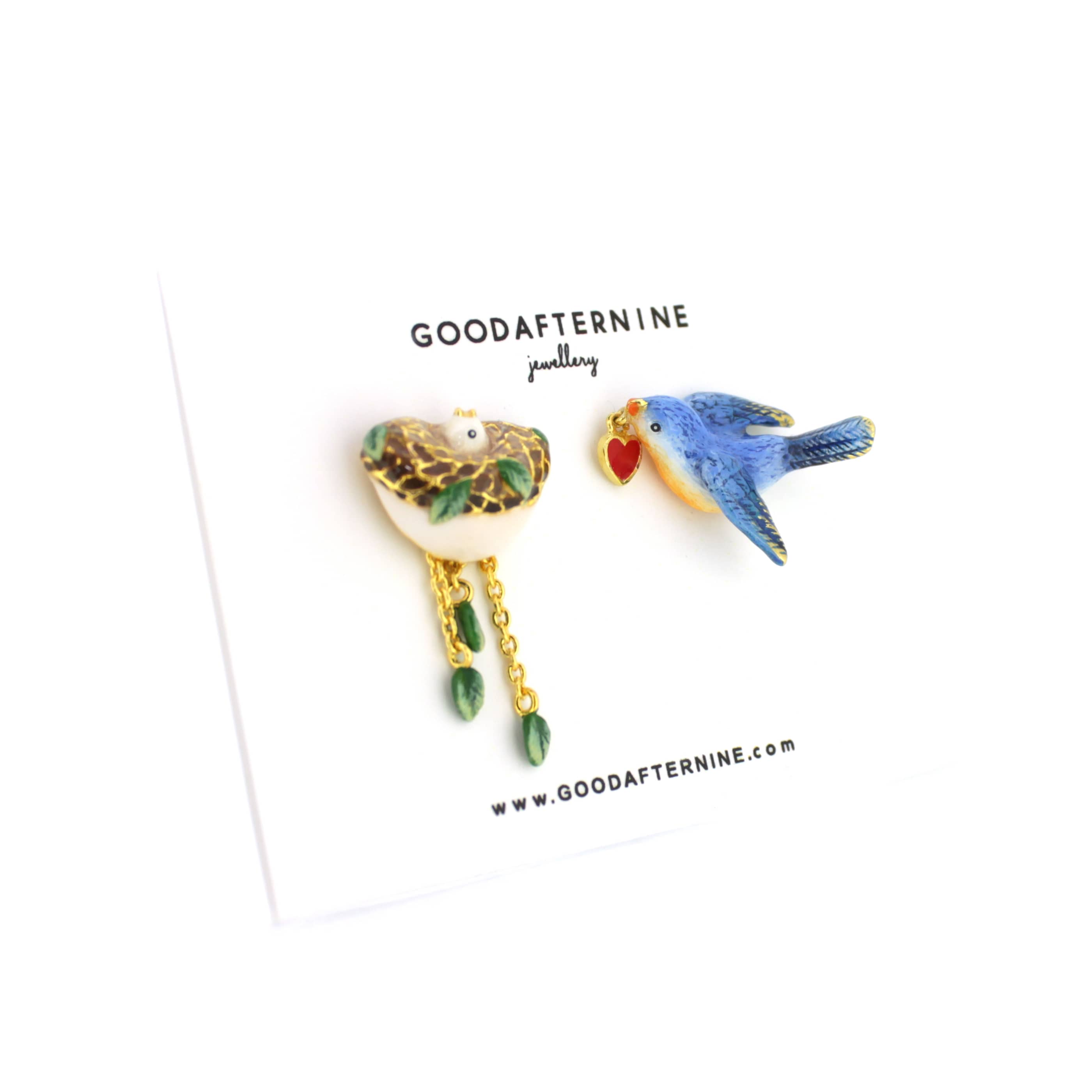 Colorful earrings featuring a bird, leaf and a nest designs, with gold accents and dangling elements.