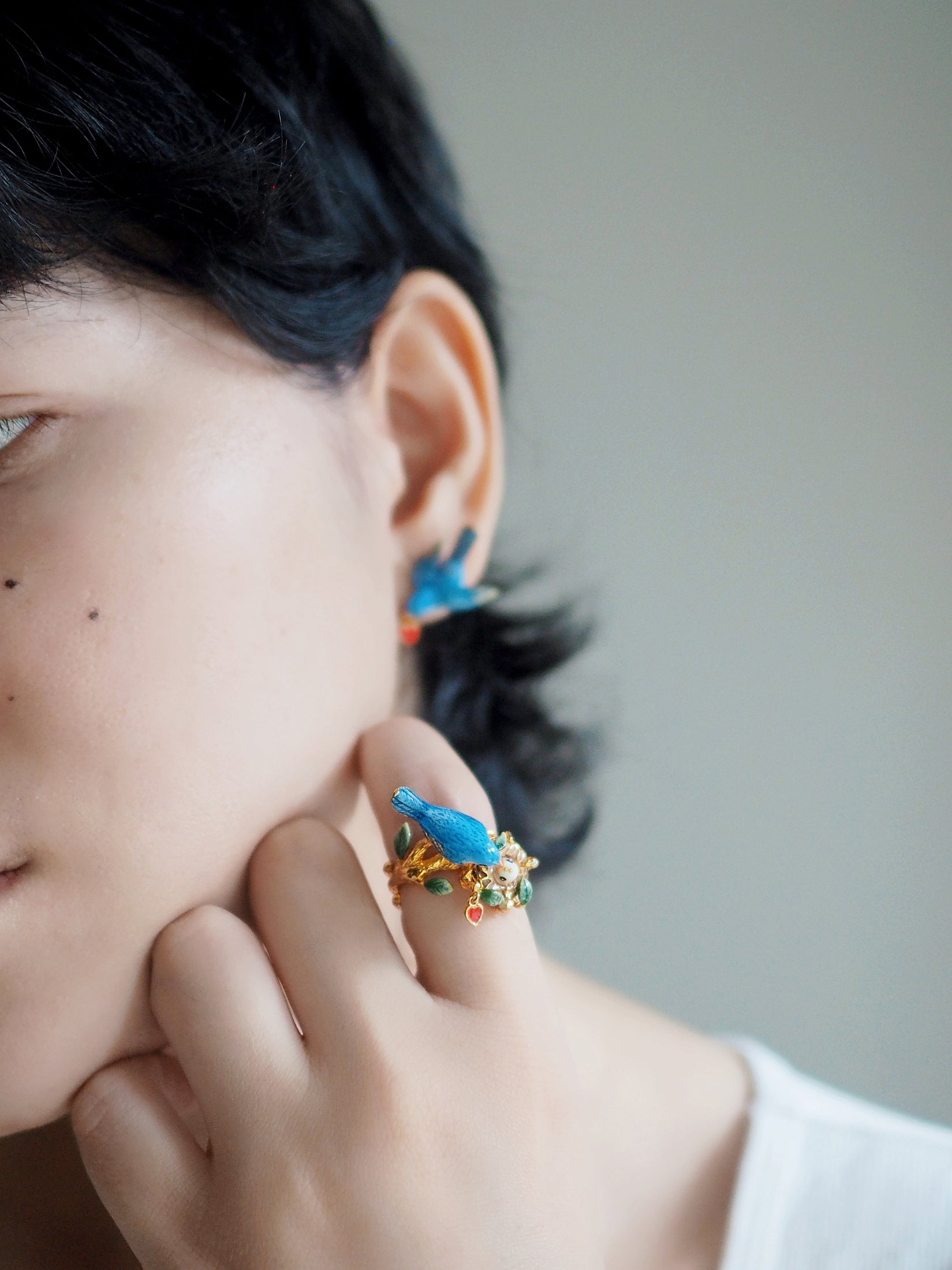 Woman wearing beautiful earring and ring featuring a bird and leaf designs