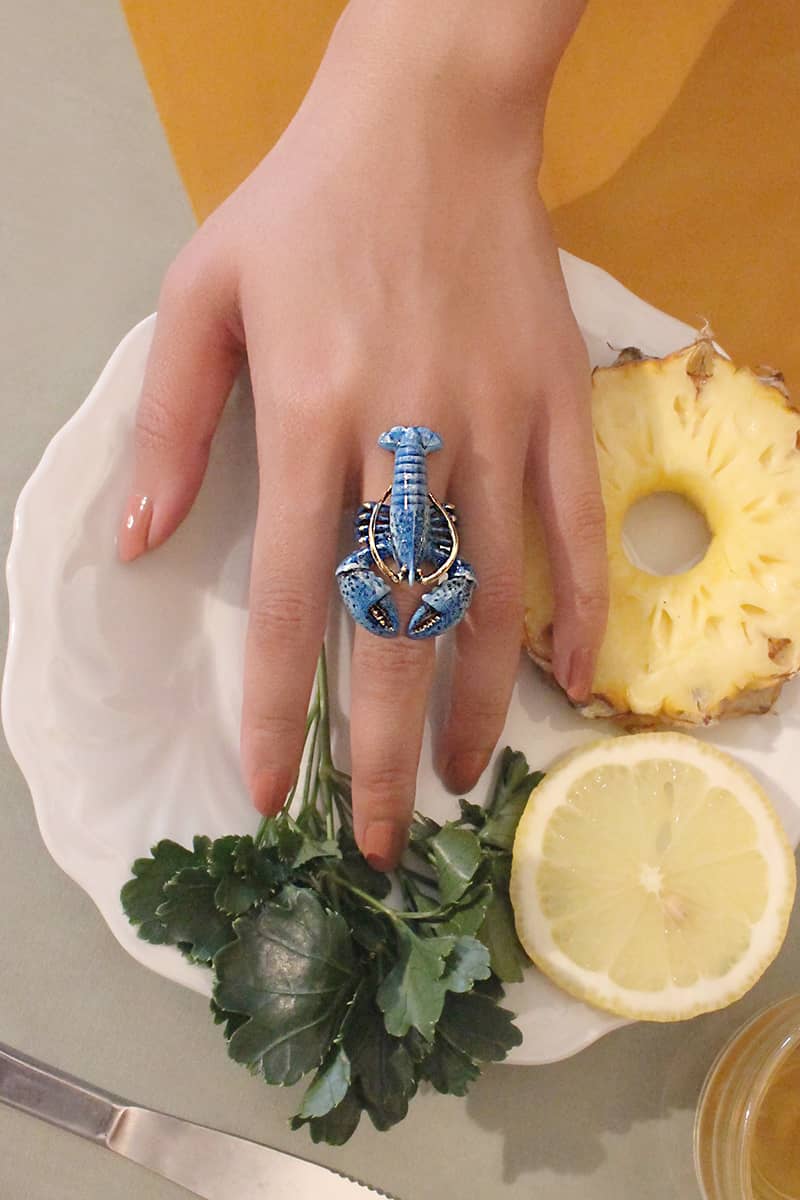 and showcasing a unique blue lobster ring surrounded by pineapple and lemon.