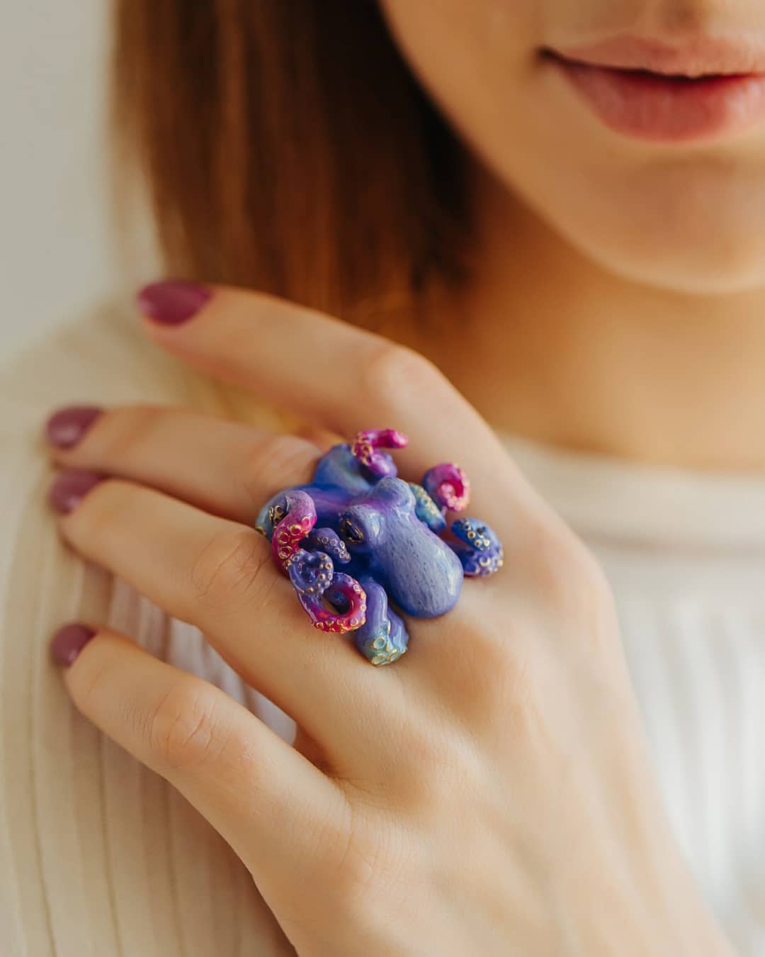 A close-up of a hand wearing a whimsical octopus ring, featuring vibrant colors.