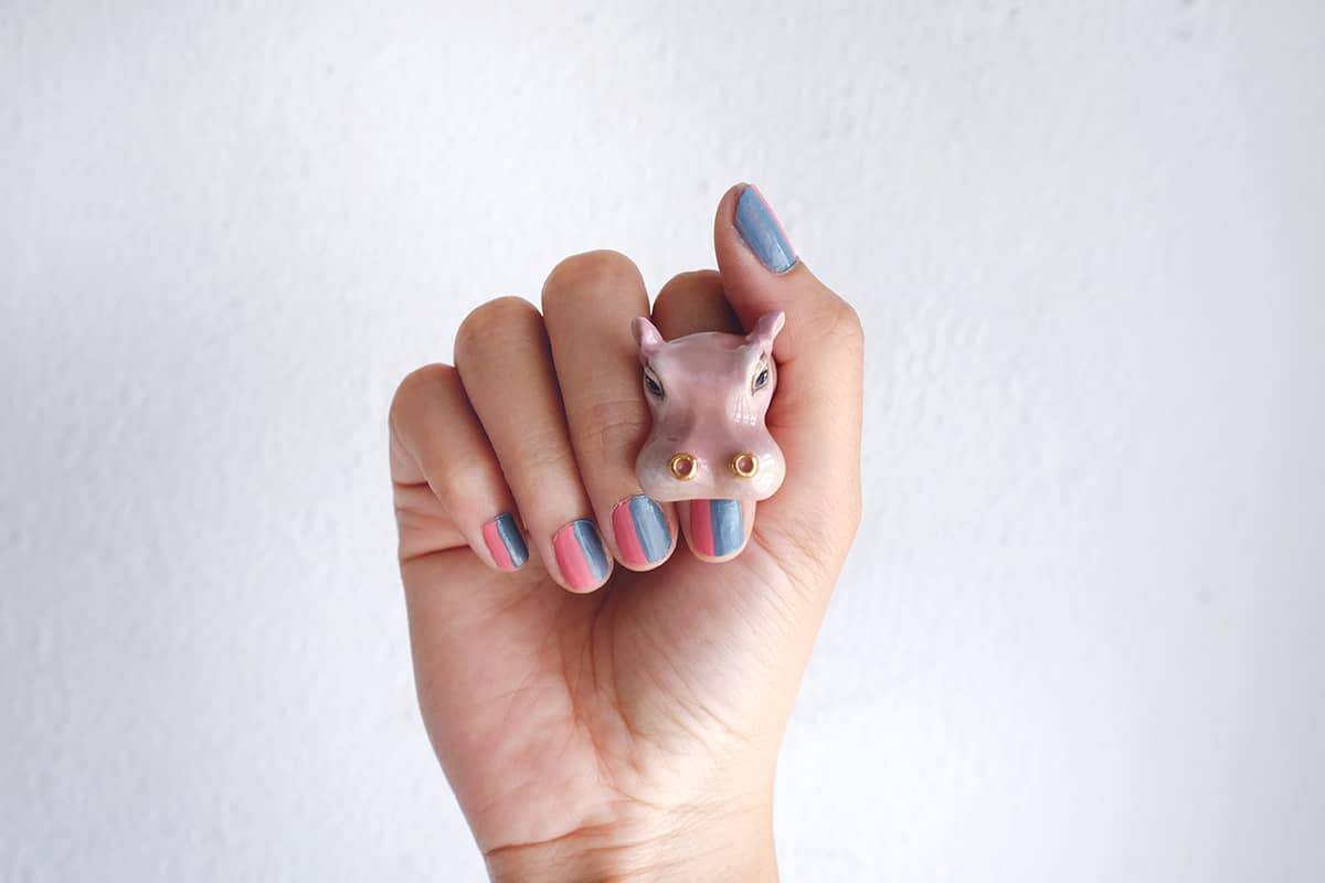 Close-up of a hand with colorful nail art and a hippo ring.