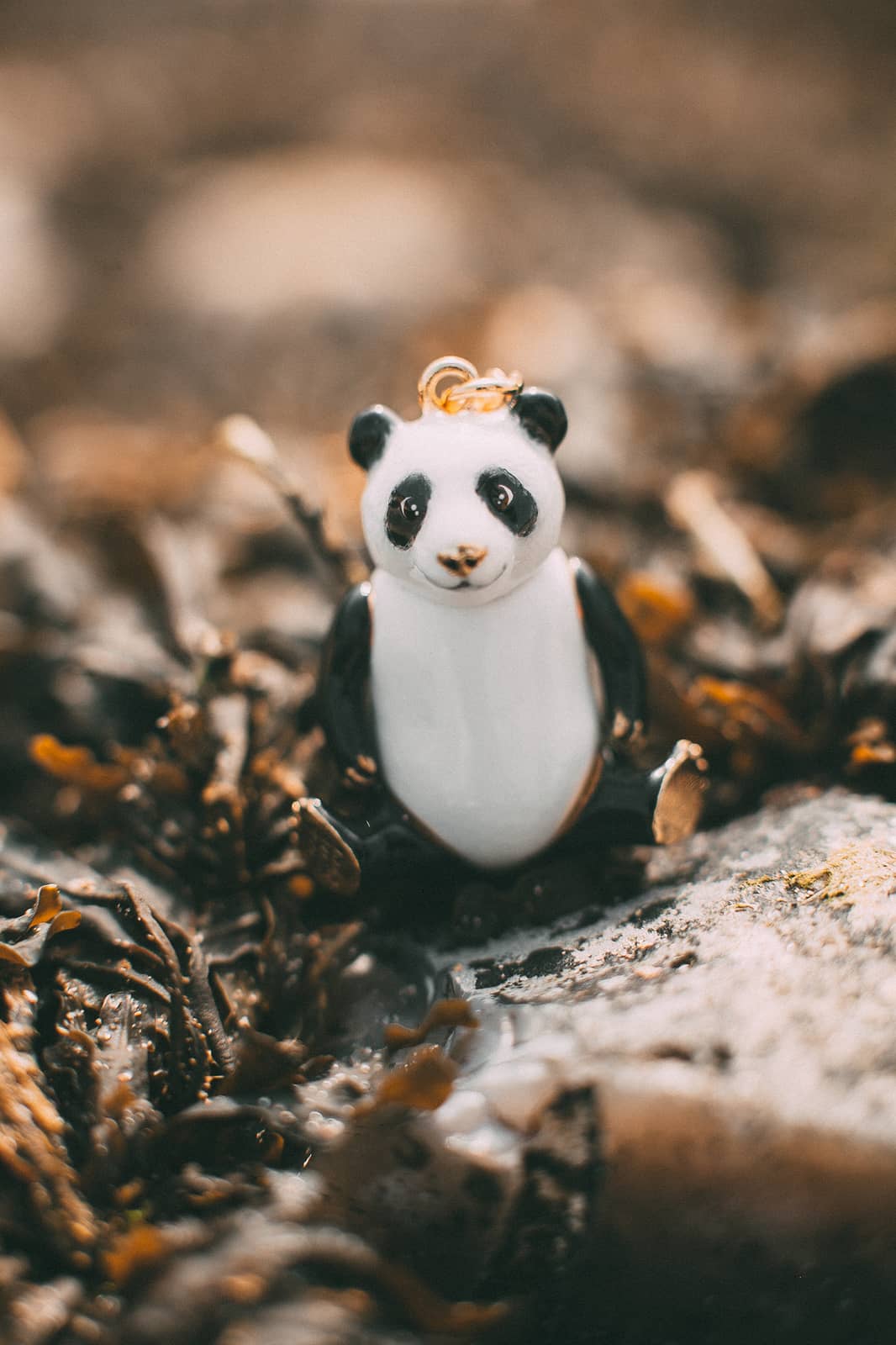 Adorable black and white panda pendant placed among natural setting.