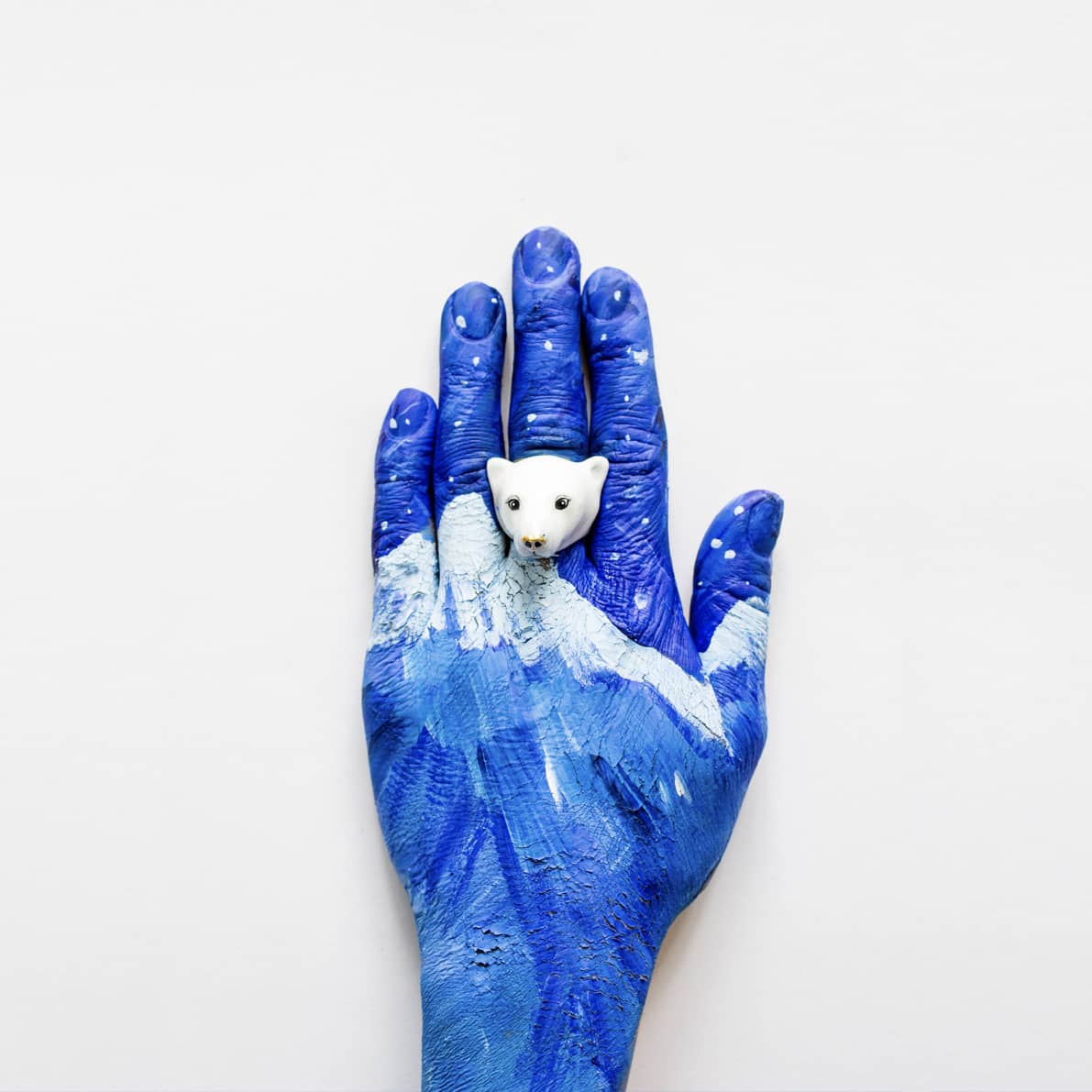 A painted blue hand with a cute polar bear ring on