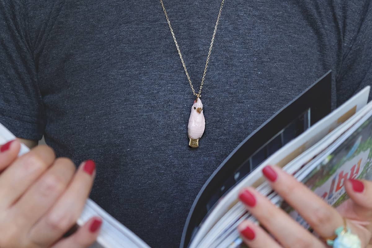 A close-up of a cute cockatoo whistle necklace worn on a person with causal outfit.