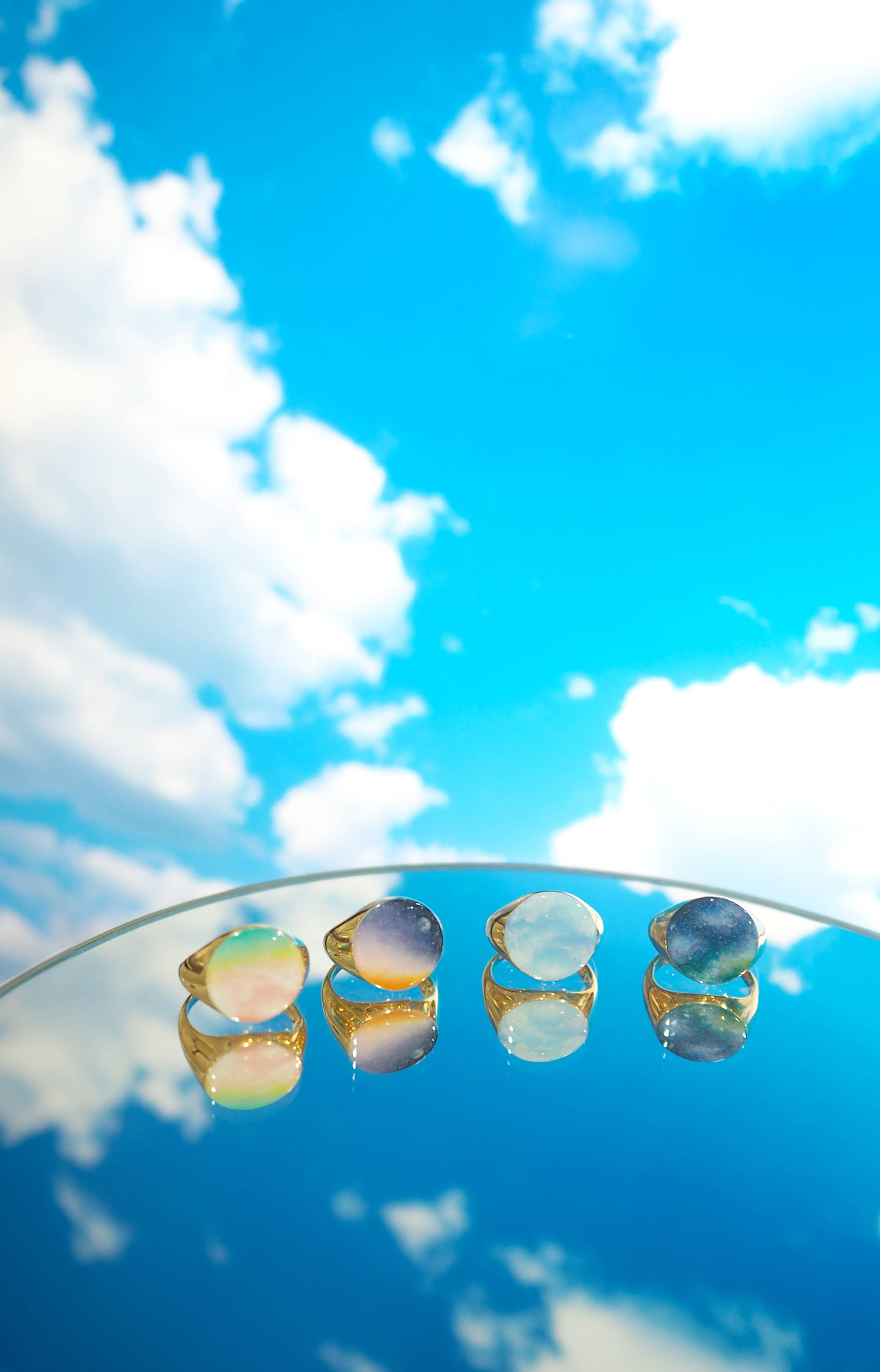 Collection of colorful hand-painted rings displayed under a bright sky.