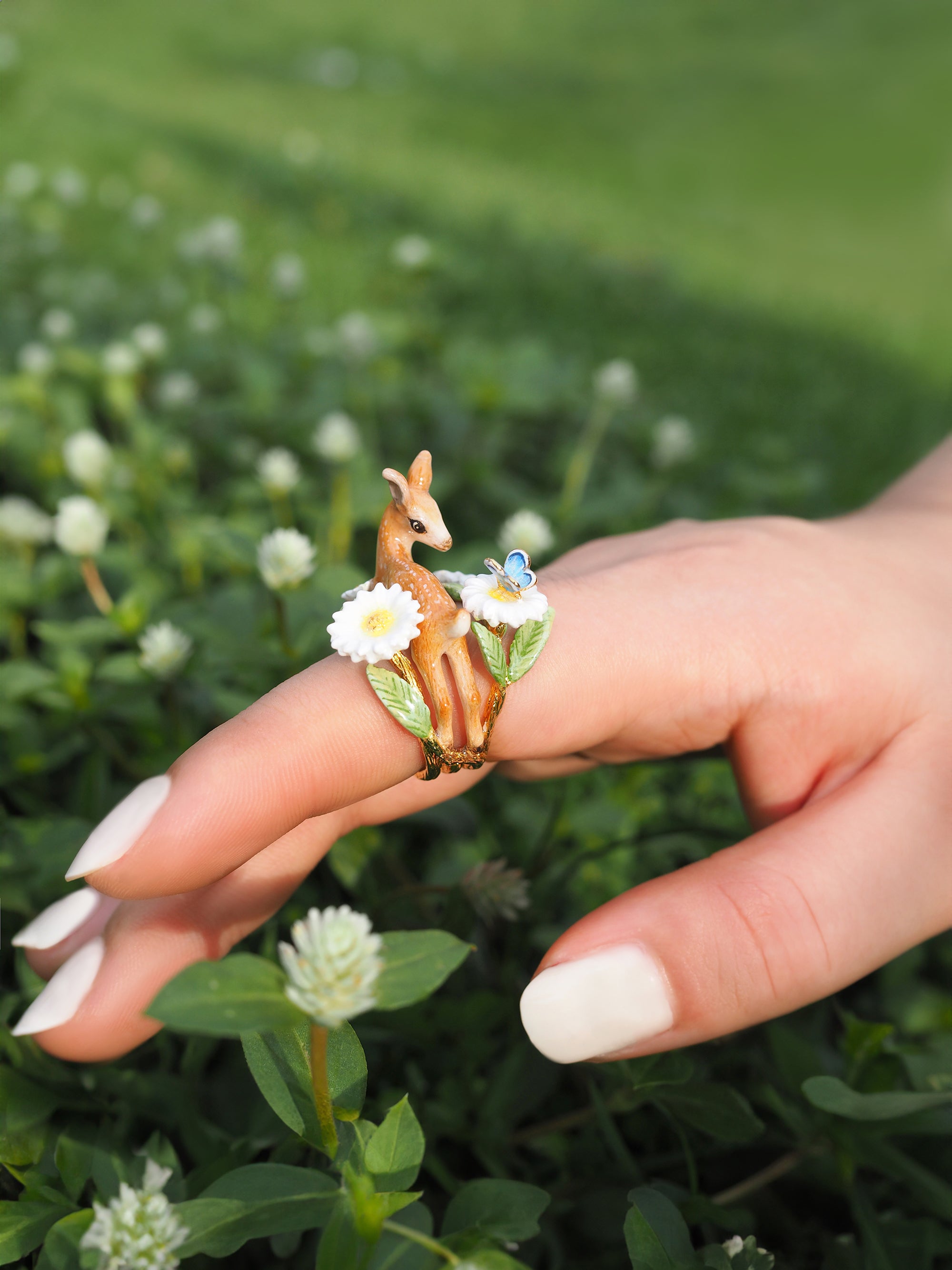 An artistic ring depicting a deer with flowers, beautifully showcased on a person's hand.