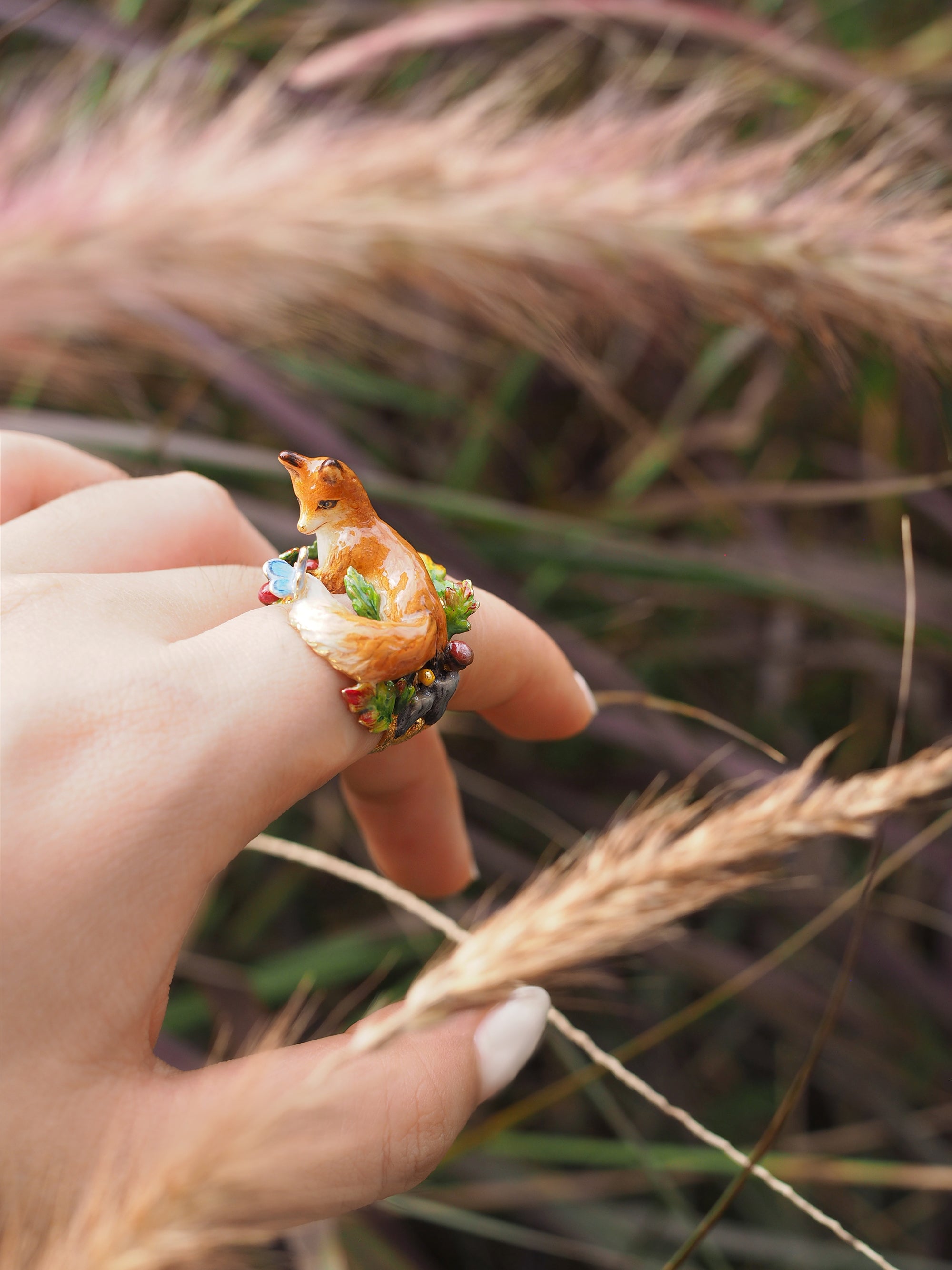 Nature-inspired ring featuring a fox, displayed on a hand in a natural setting.