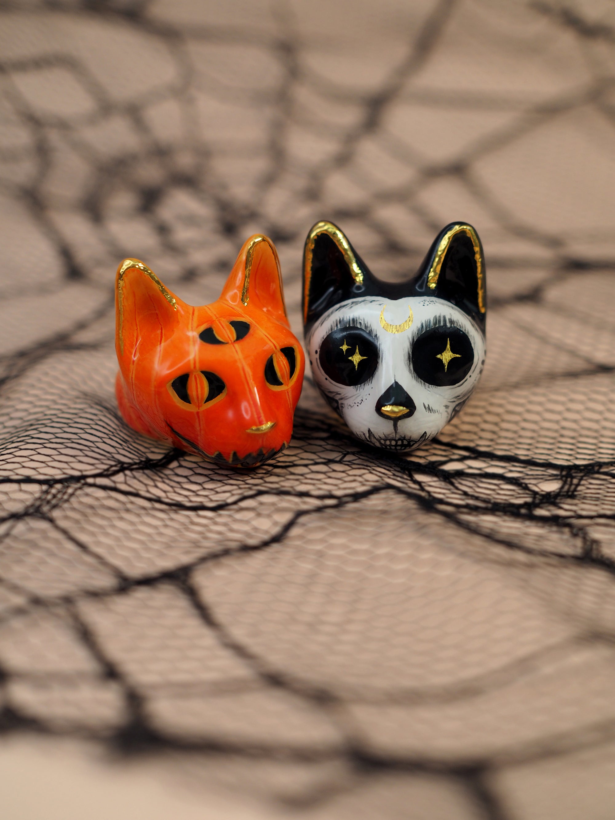 Two Halloween-themed cat rings set on decorative spider web.