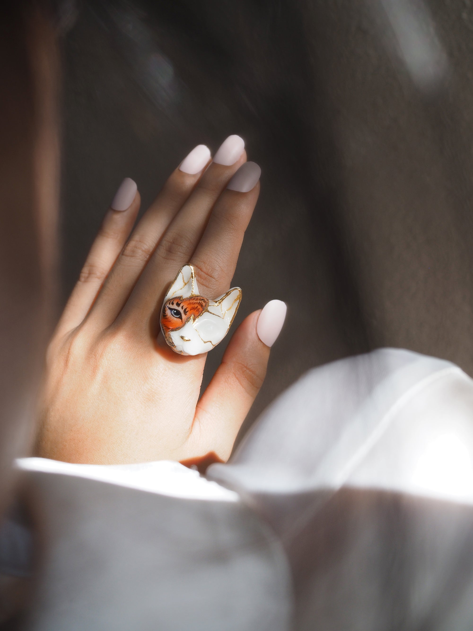 Close-up of a hand wearing a cat ring blending feline and tiger features.