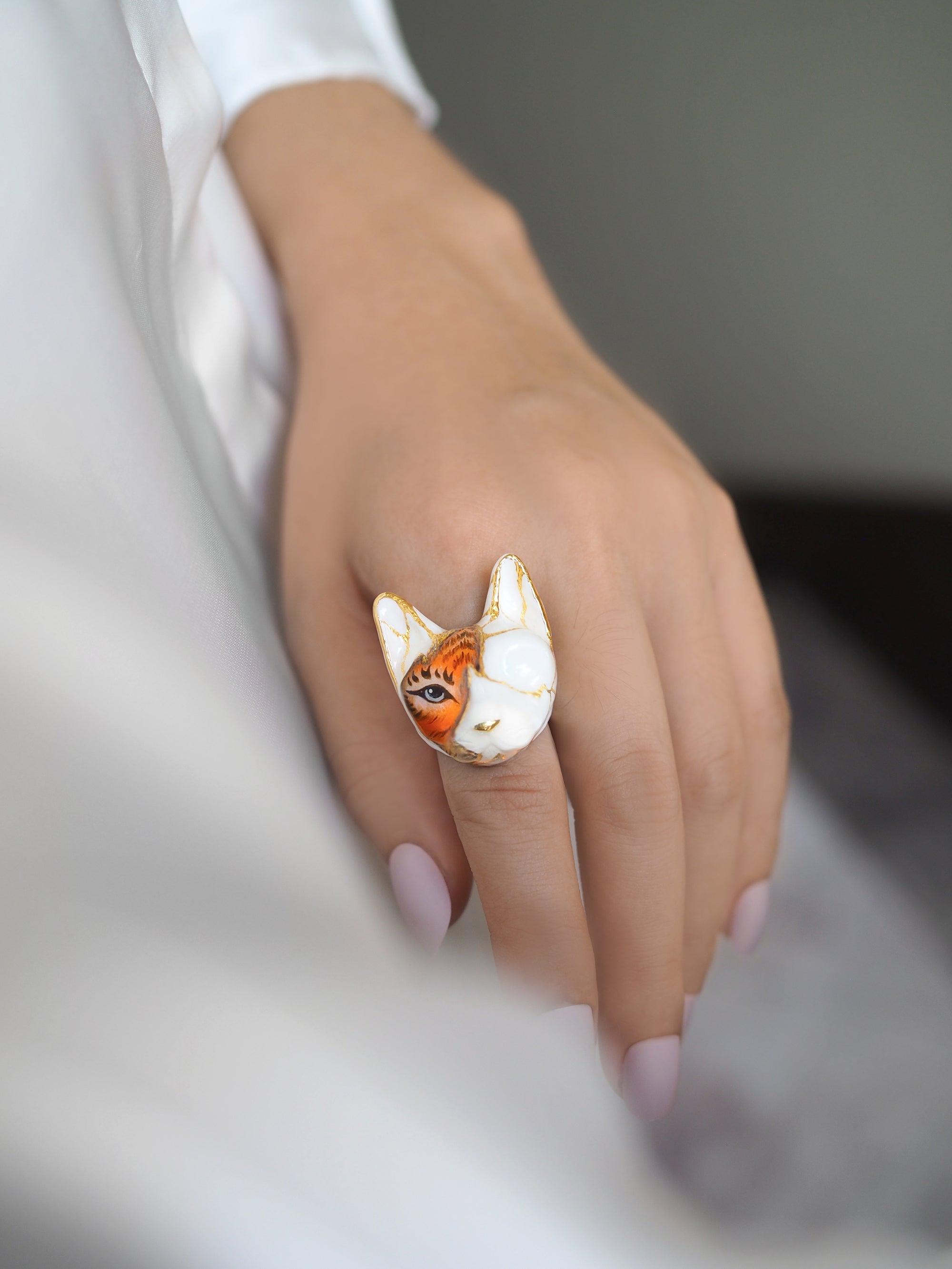 Close-up of a hand wearing a cat ring blending feline and tiger features.