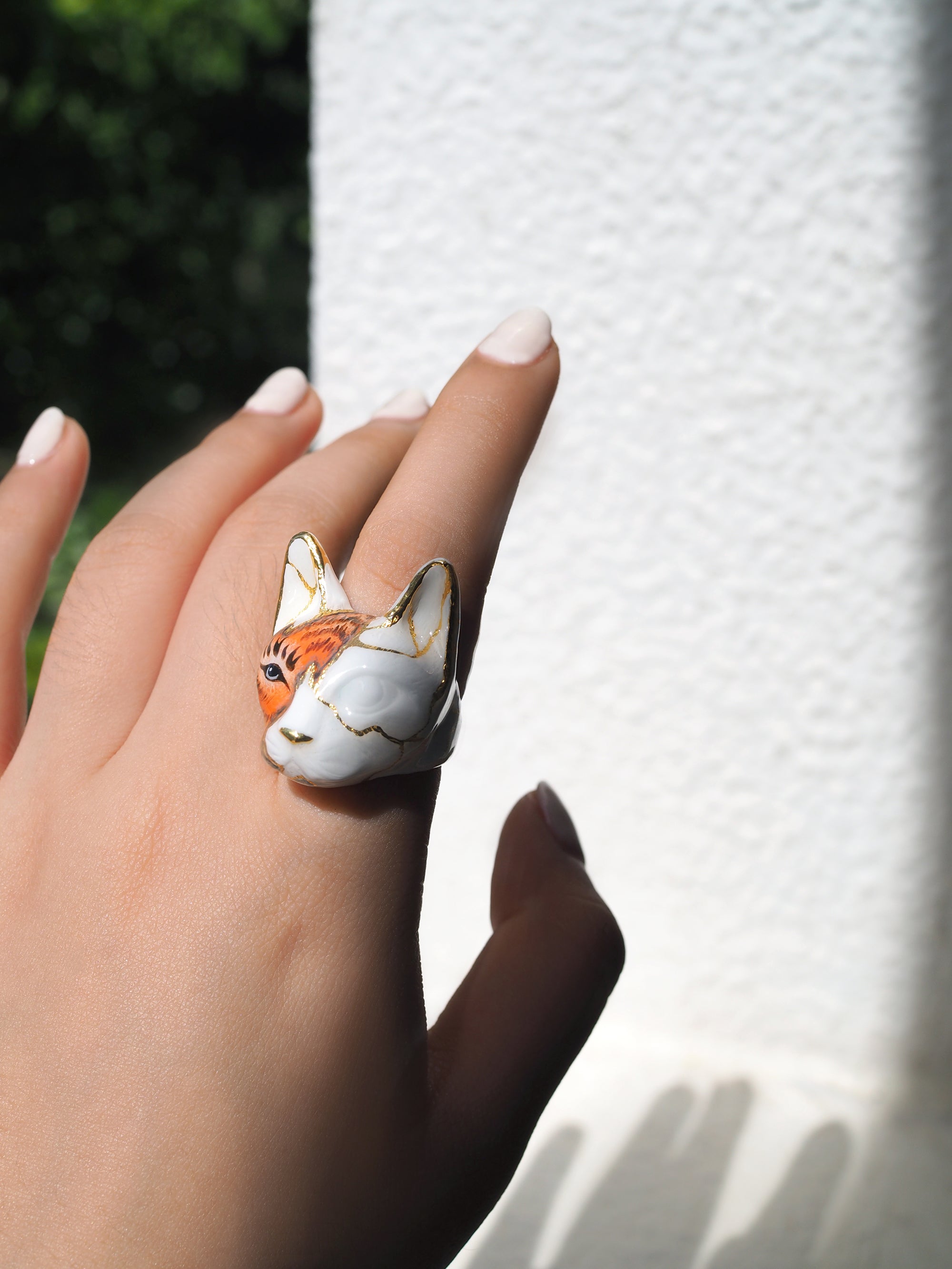 Close-up of a hand wearing a cat ring blending feline and tiger's face.