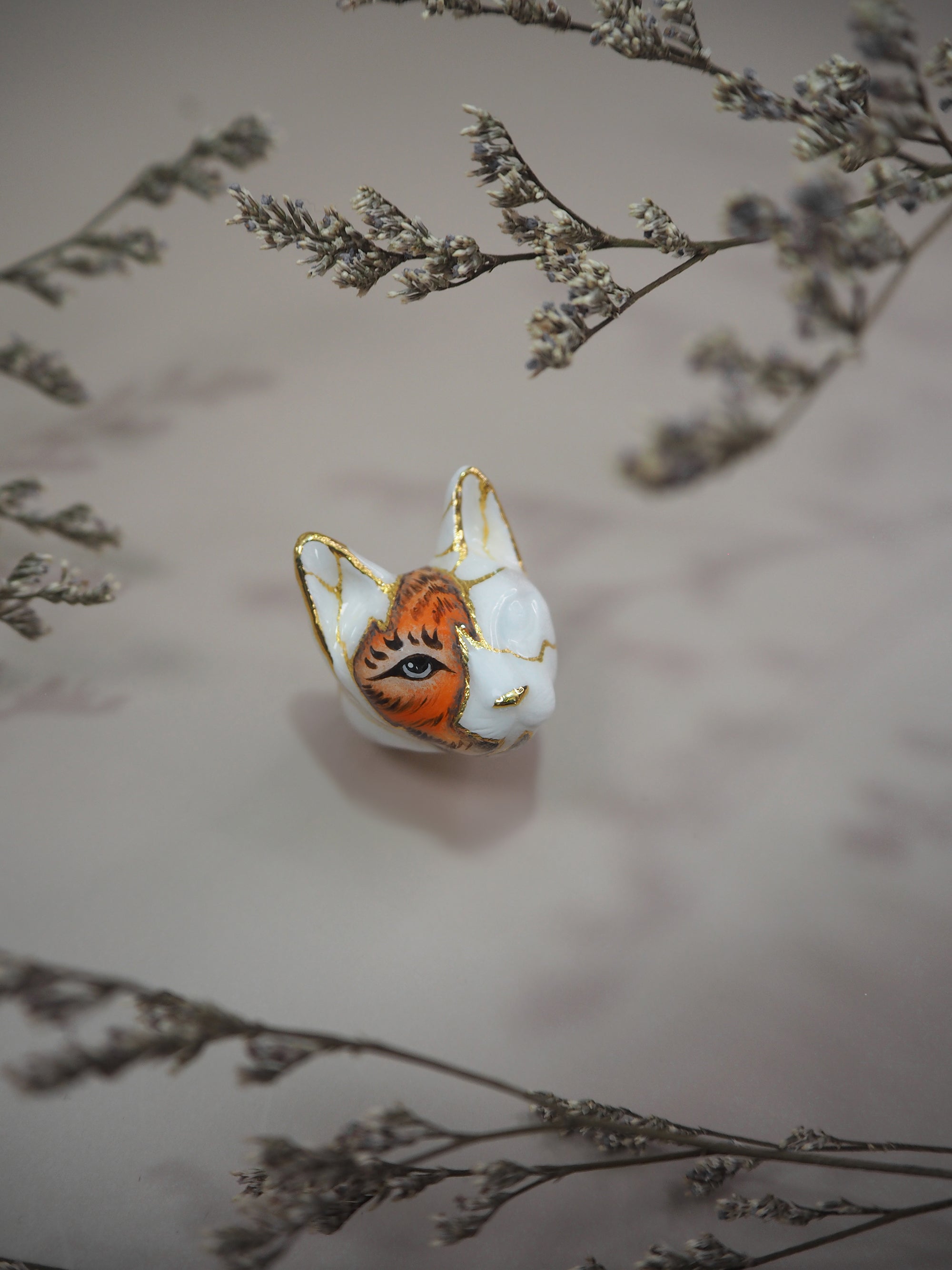 Artistic representation of a cat ring showcasing a tiger's face, surrounding by dried flowers.