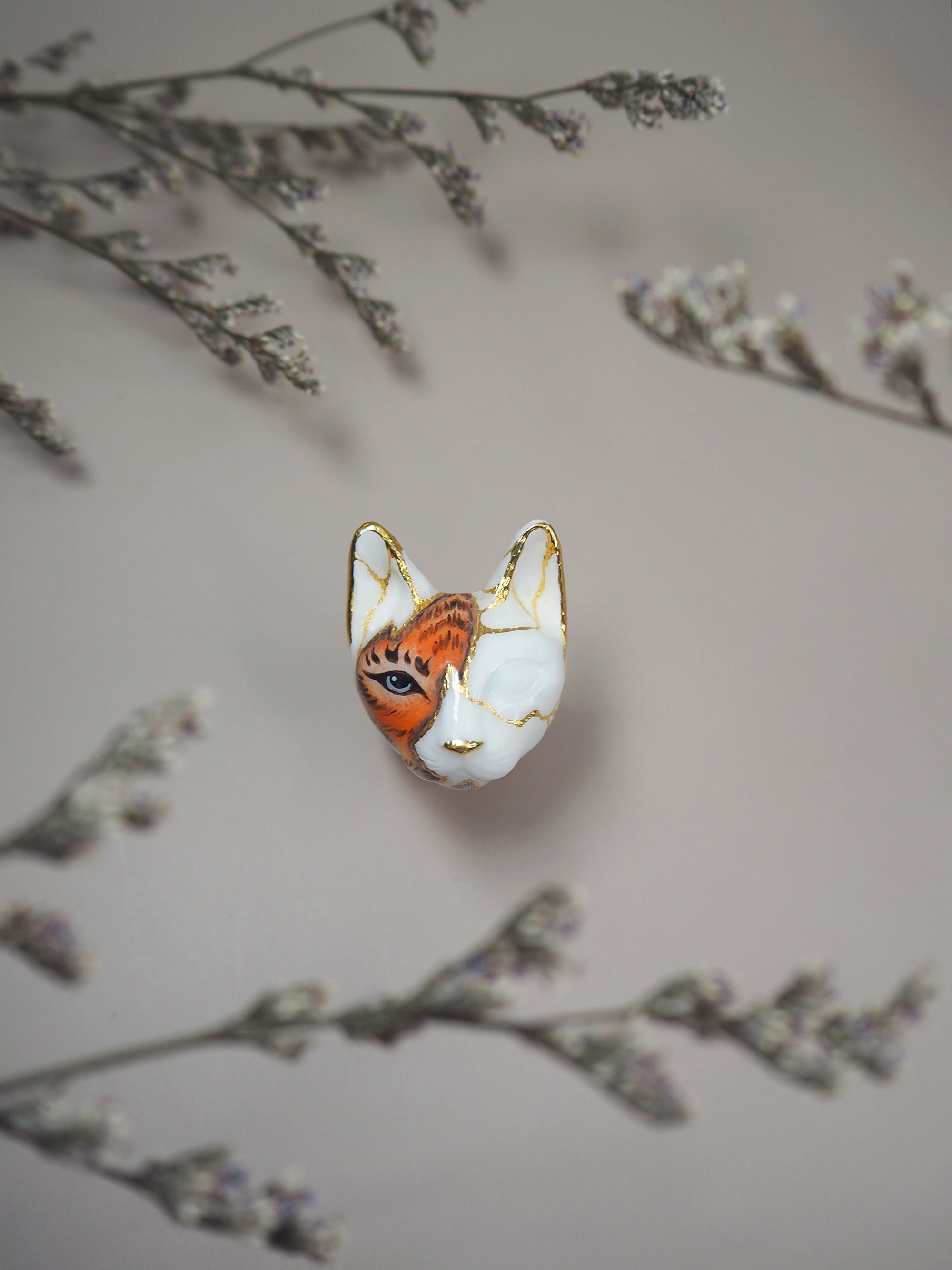 Artistic representation of a cat ring showcasing a tiger's face, surrounding by dried flowers.