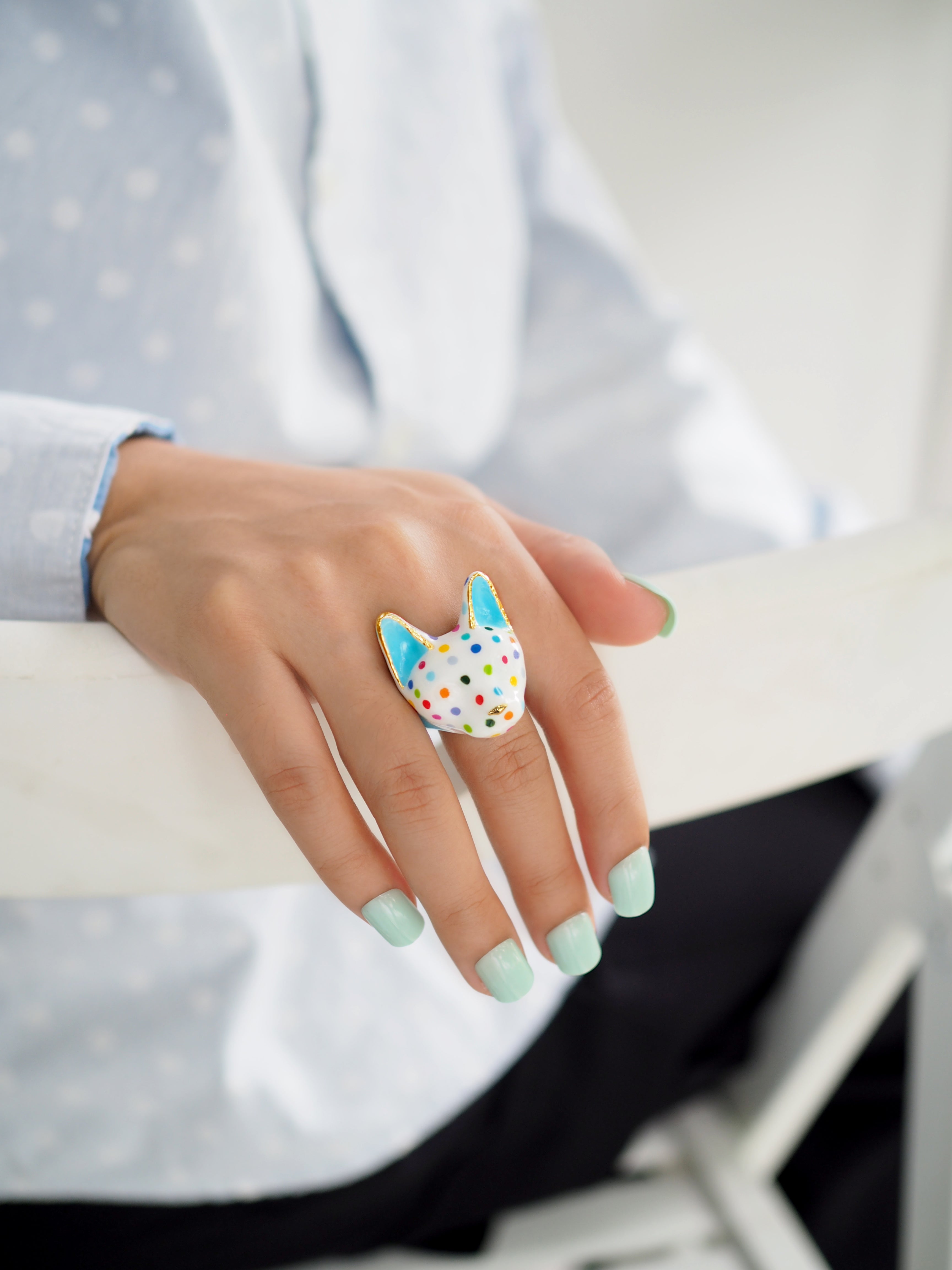 A playful cat-shaped ring with polka dots on a model's hand.