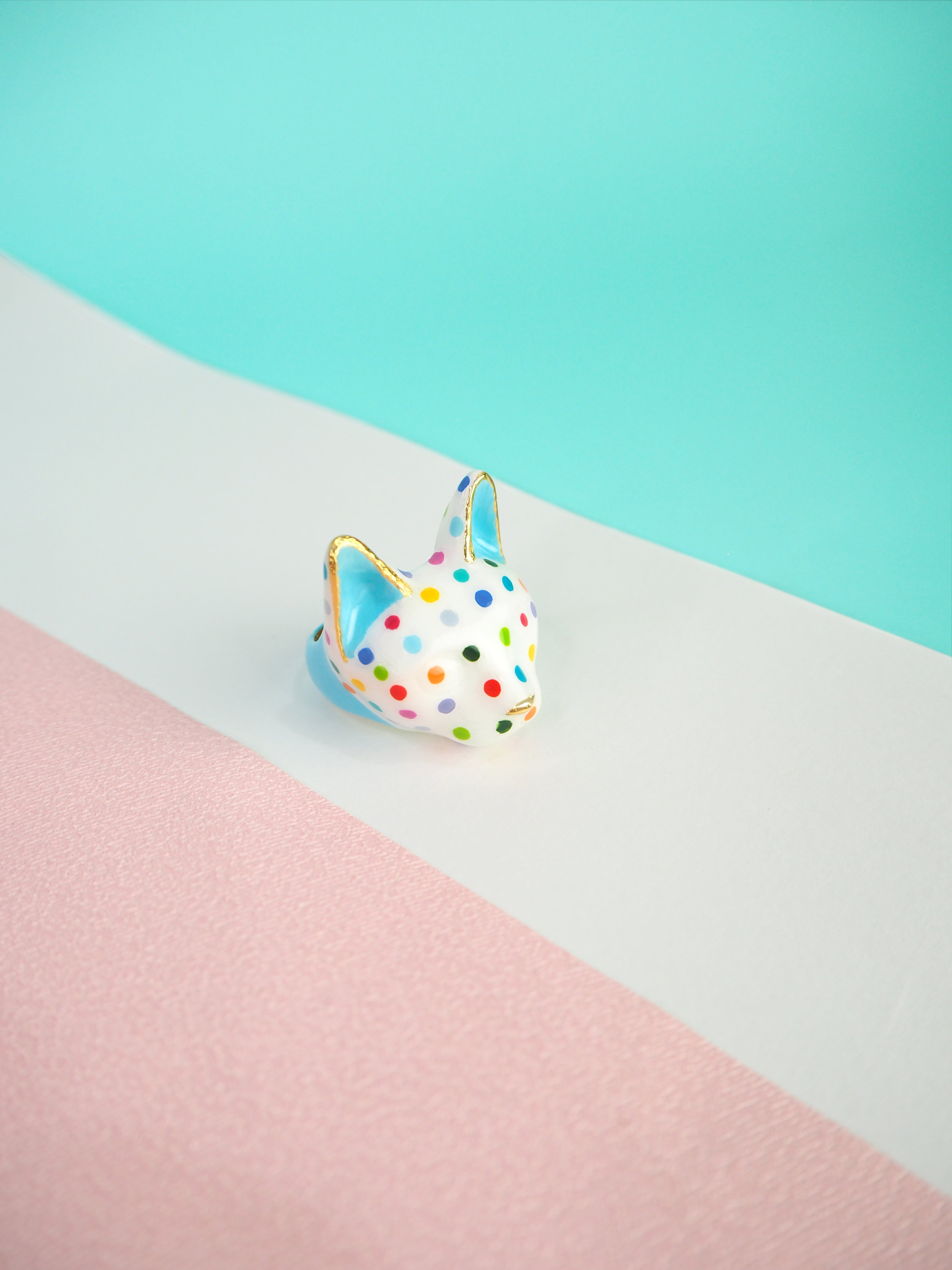 A colorful cat ring with polka dots on a pastel background.