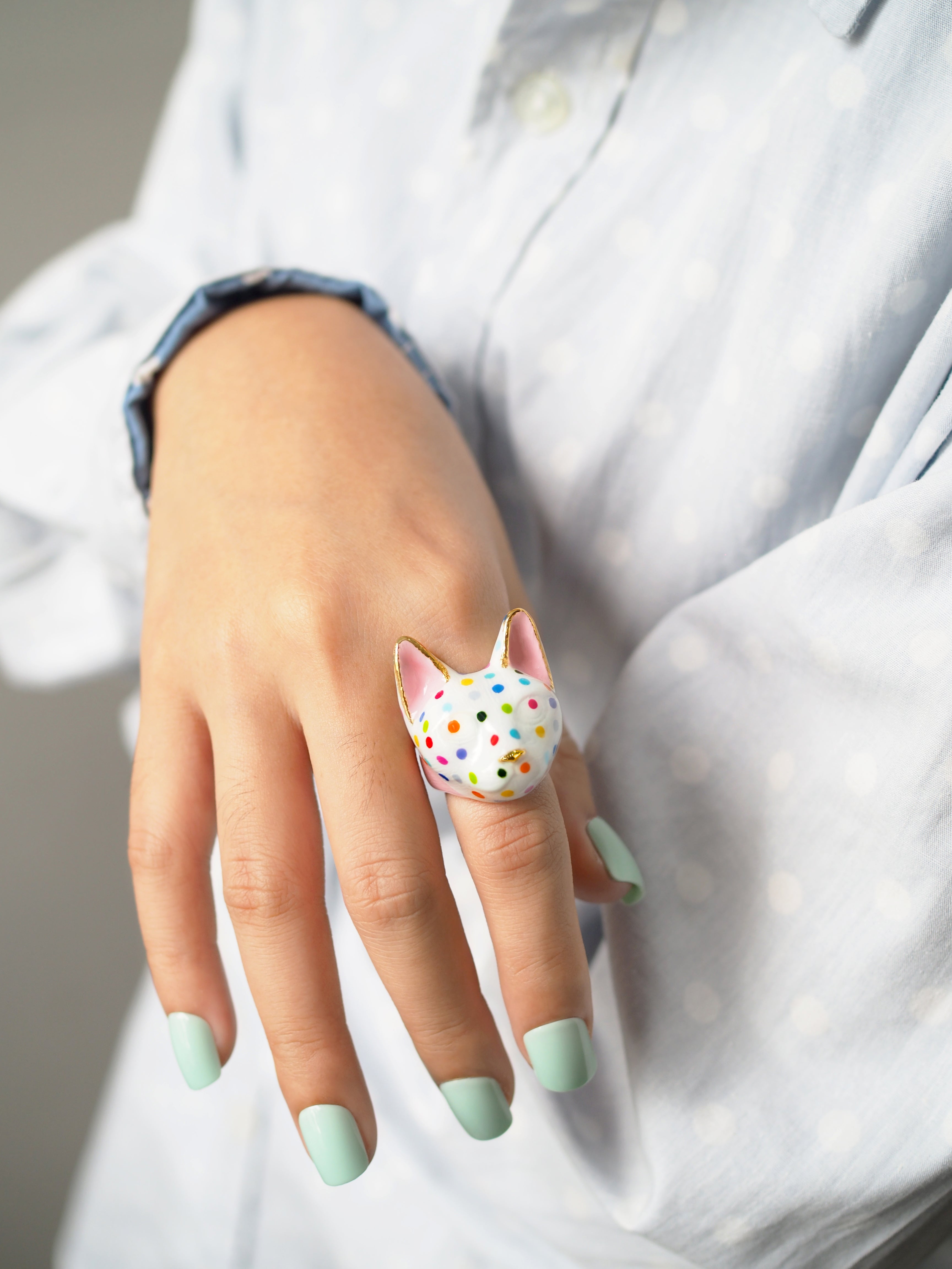 A playful cat-shaped ring with polka dots on a model's hand.