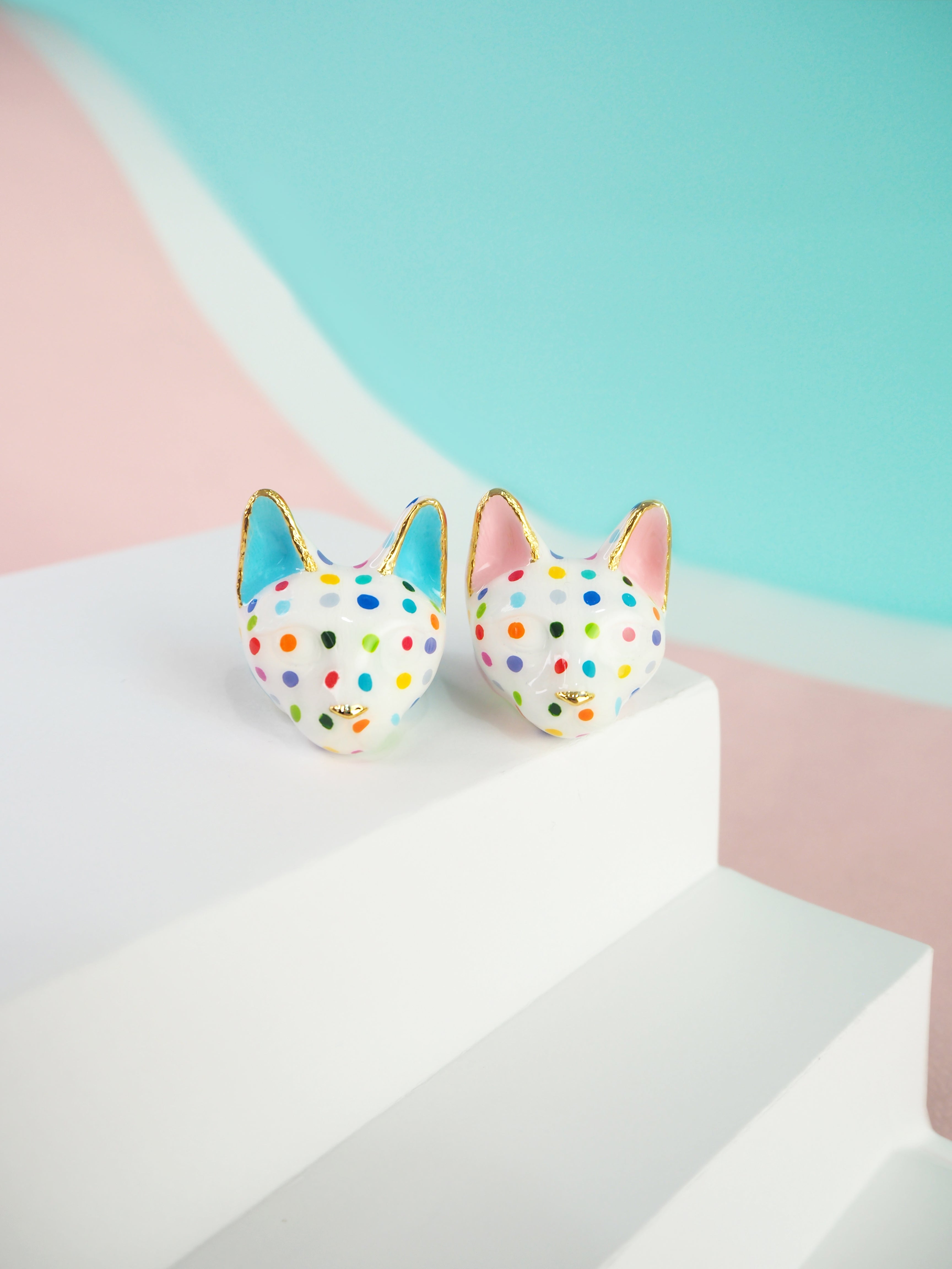 Two colorful cat rings with polka dots on a pastel background.