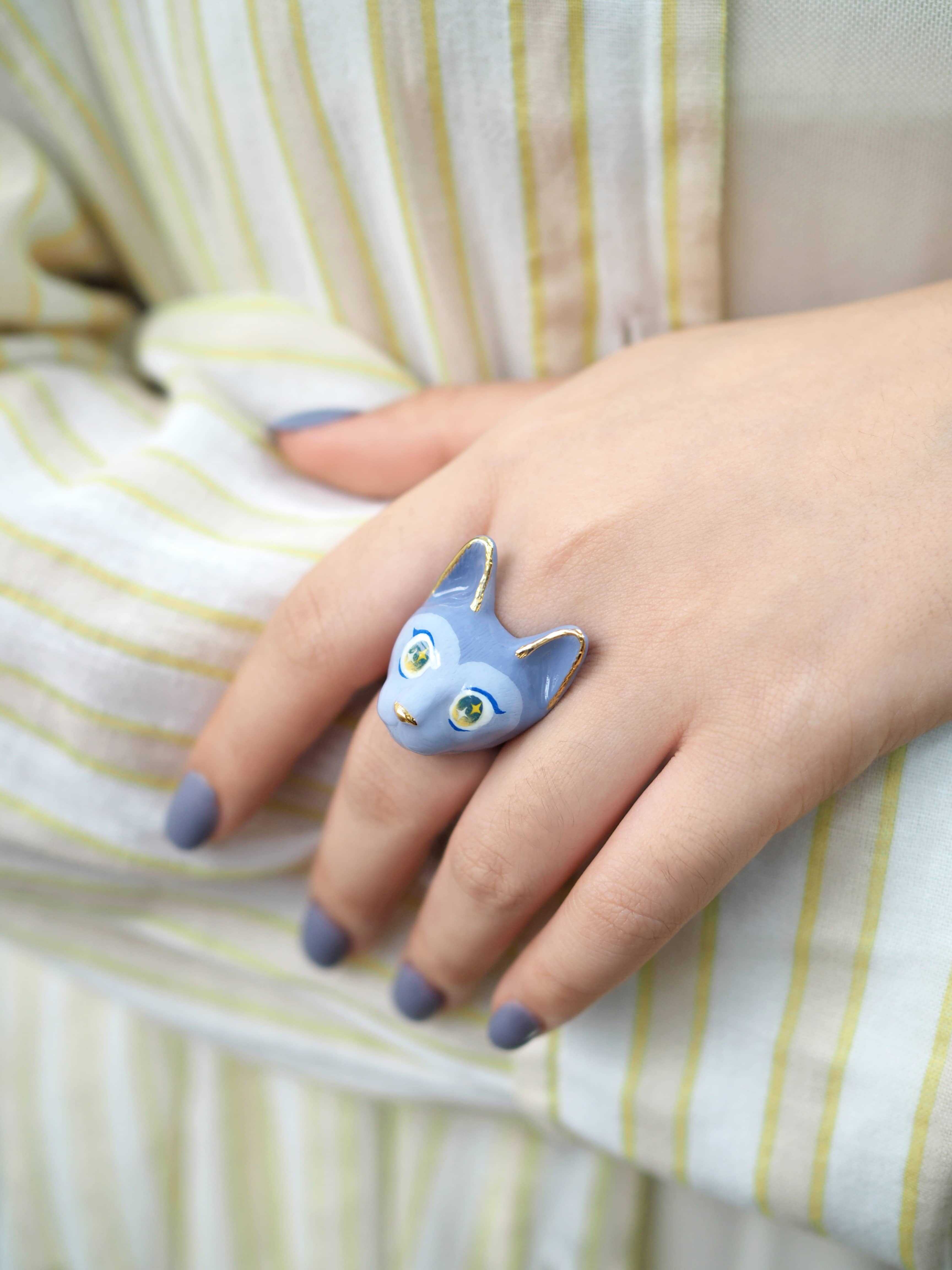 Playful cat ring featuring a whimsical design in purple hues on a hand with matching nails.